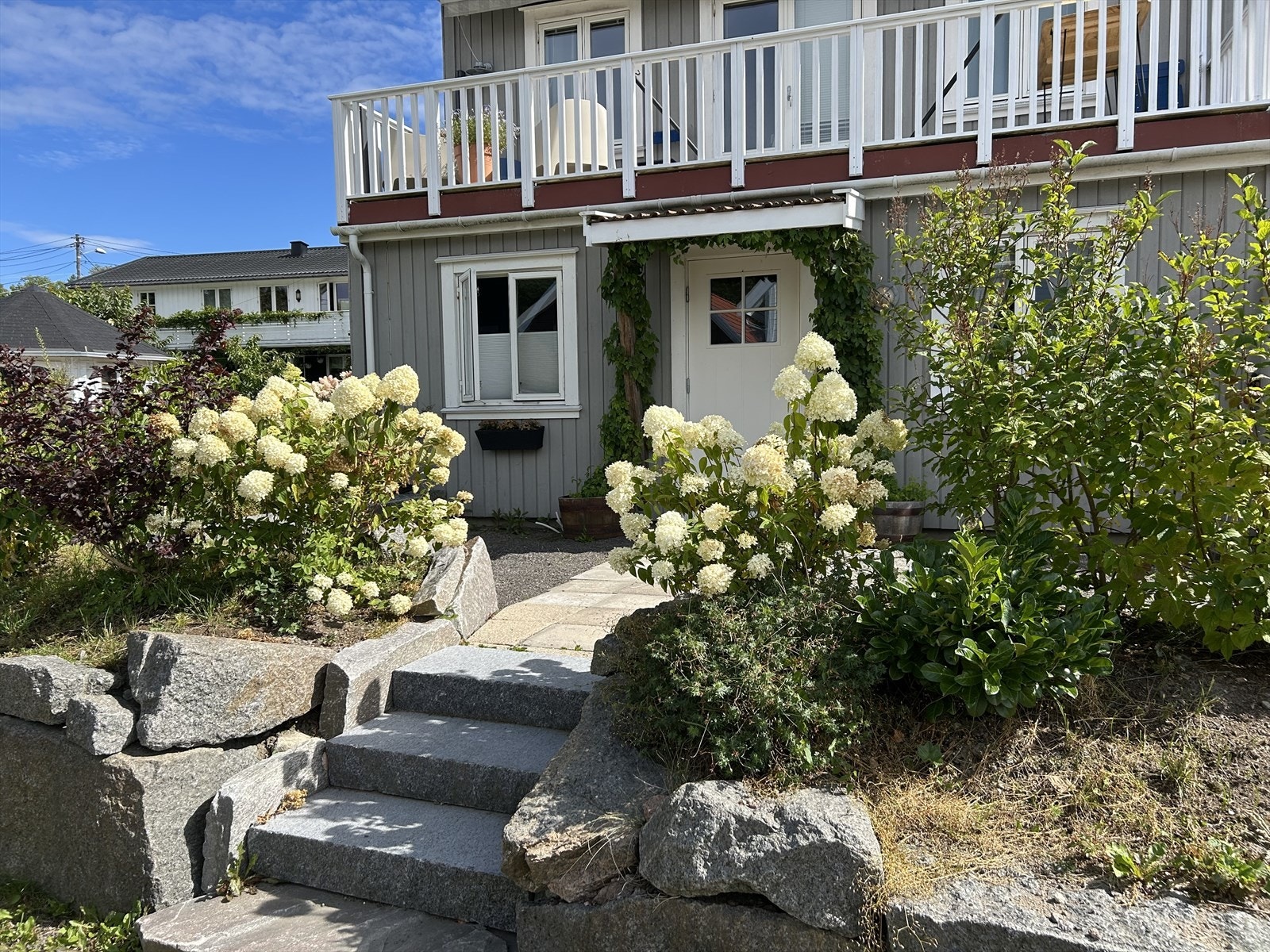 På sommeren har man et skjermet inngangsparti med vakker beplantning Galleribilde