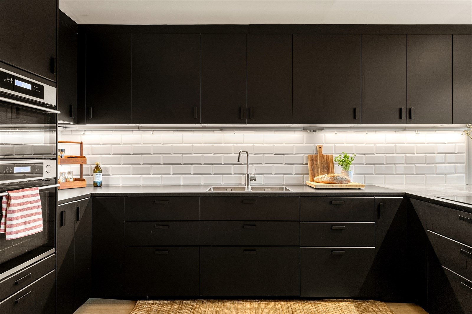 Laminat og betong benkeplate med innfelt kum, samt fliser mellom benk og overskap. Avtrekksvifte og kullfilter integrert i benkeplaten. Galleribilde