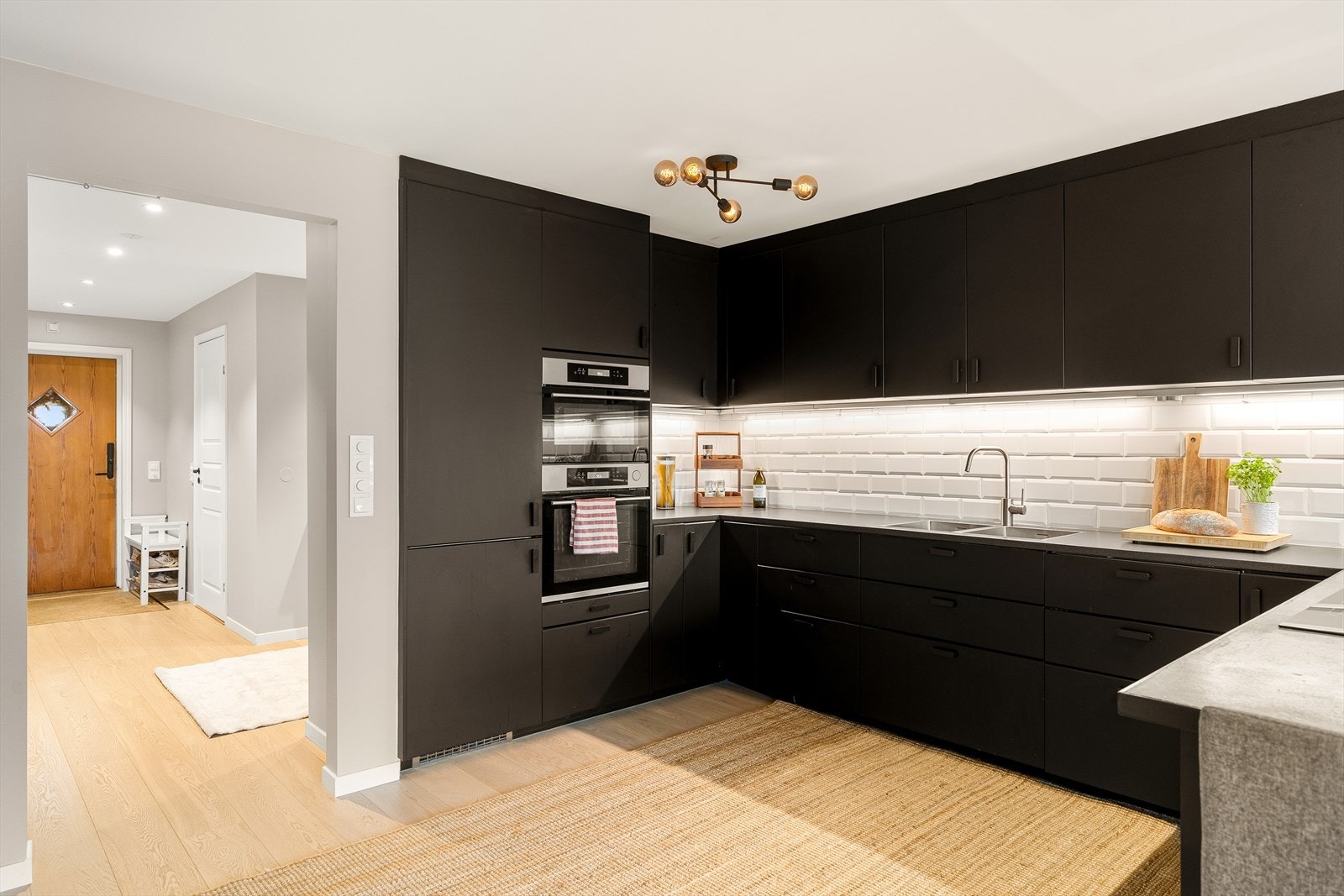 Pent kjøkken med store arbeidsflater og rikelig skapplass. Tidsriktig kjøkkeninnredning fra 2018 med integrerte hvitevarer som komfyr, koketopp, oppvaskmaskin, kjøleskap og fryser. Galleribilde