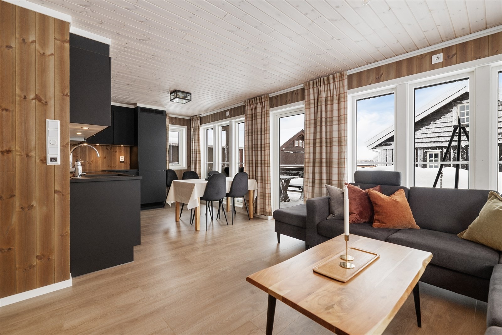 Stua og kjøkkenet har en sosial og åpen løsning, hvor beisede trepaneler og flott parkettgulv gir rommet et lunt og levende uttrykk med et varmt preg. Galleribilde