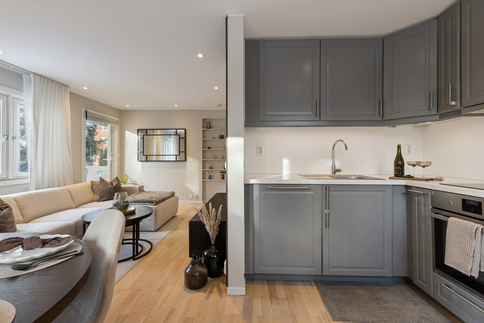 Kjøkkenet har en takhøy IKEA-innredning med grå profilerte fronter og hvit laminert benkeplate. Galleribilde