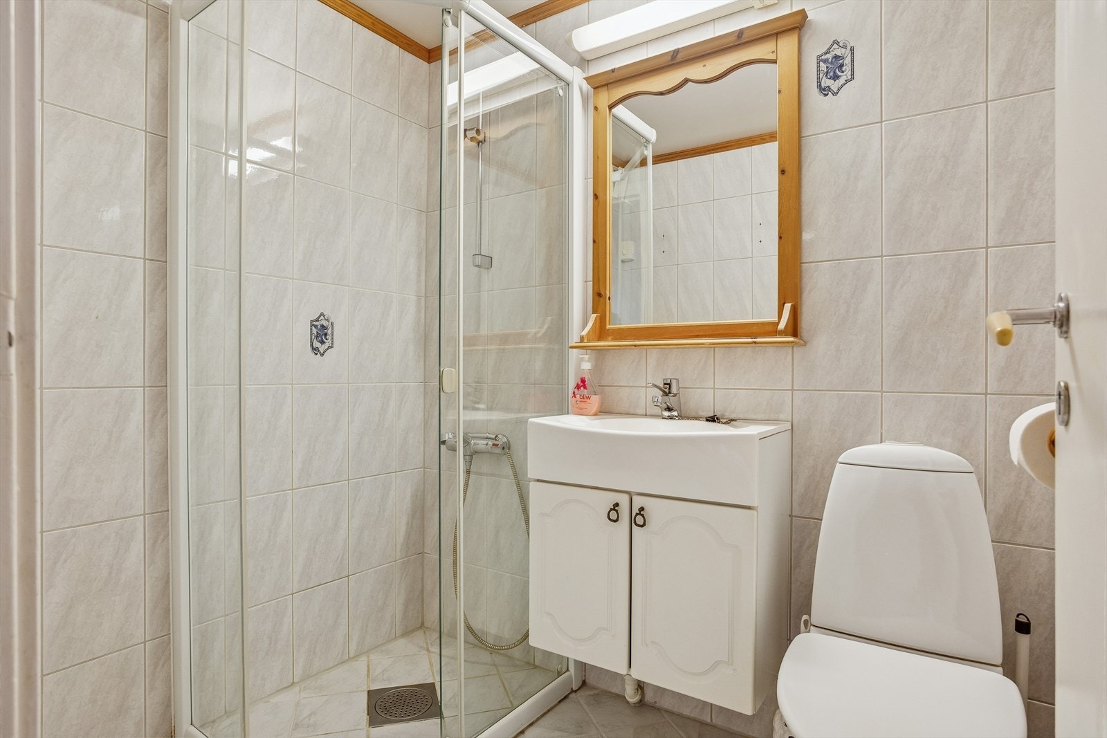 Badet er fra 1990-tallet med keramiske fliser, dusjhjørne med glassvegger og gulvmontert toalett. Galleribilde