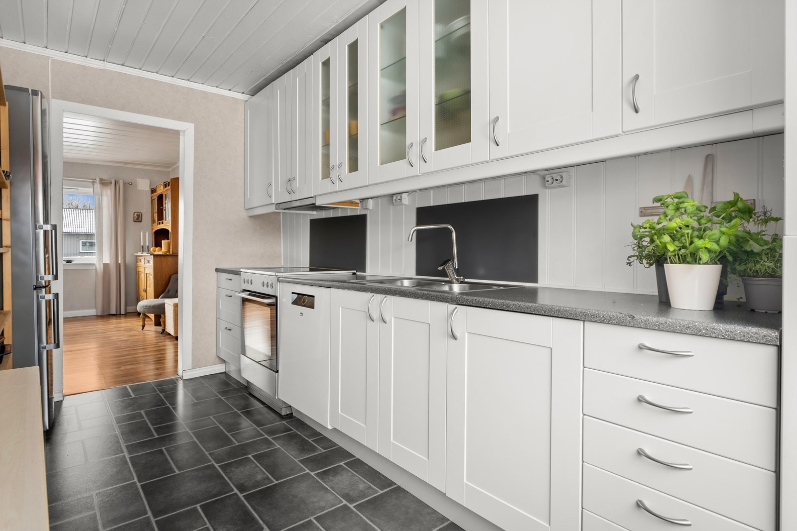 Benkeplaten i laminat er utstyrt med oppvaskkum og sprutsikre plater på veggen. Galleribilde