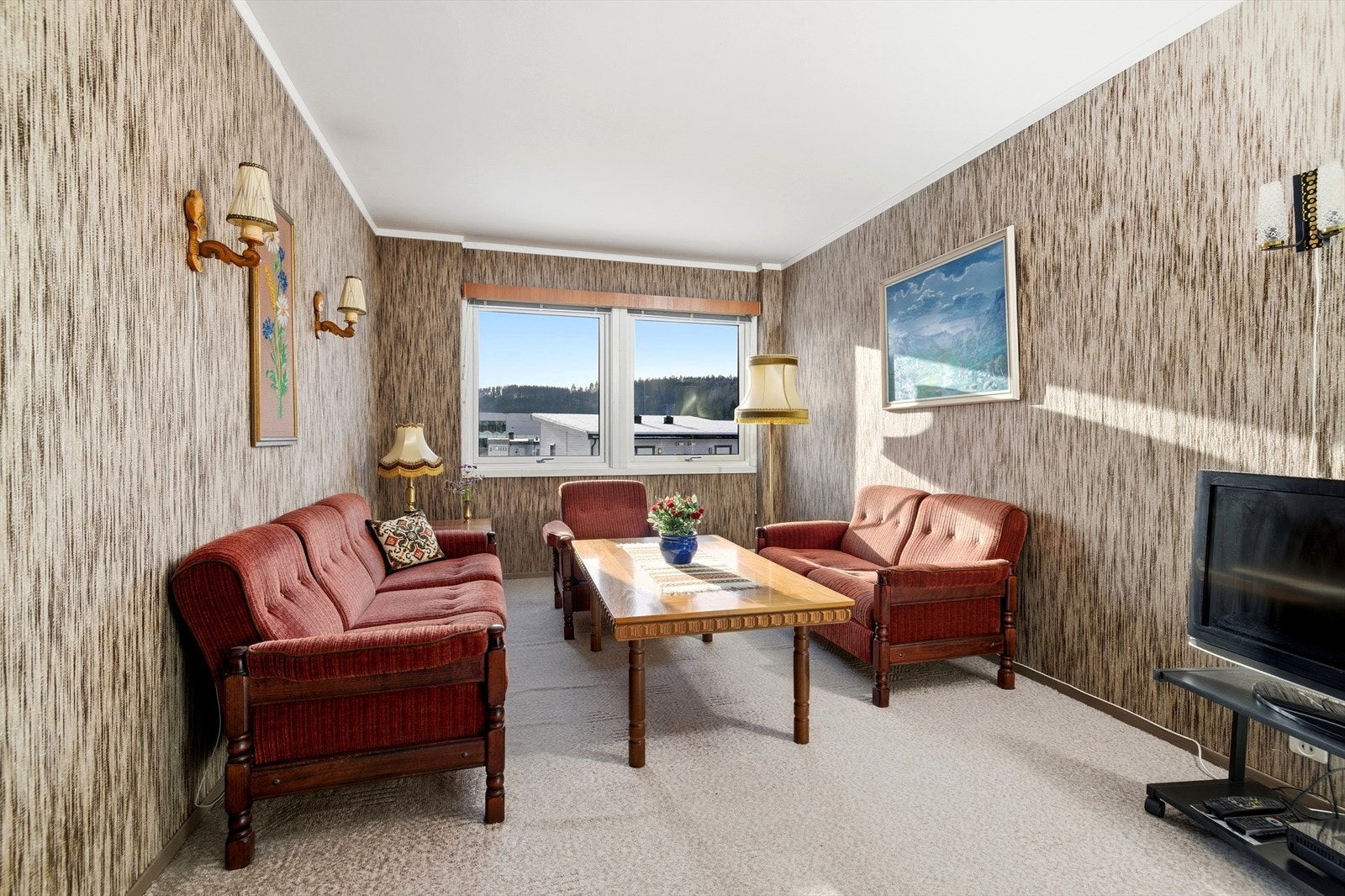 Overflatene i stuen består av teppegulv og tapetserte vegger. Galleribilde