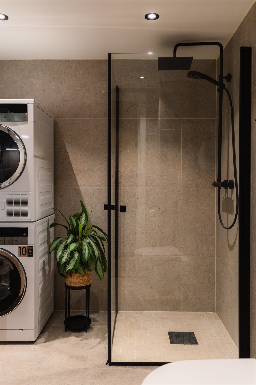 Dusjhjørne med innfellbare glassdører i sort profil og regnfallsdusj. Galleribilde