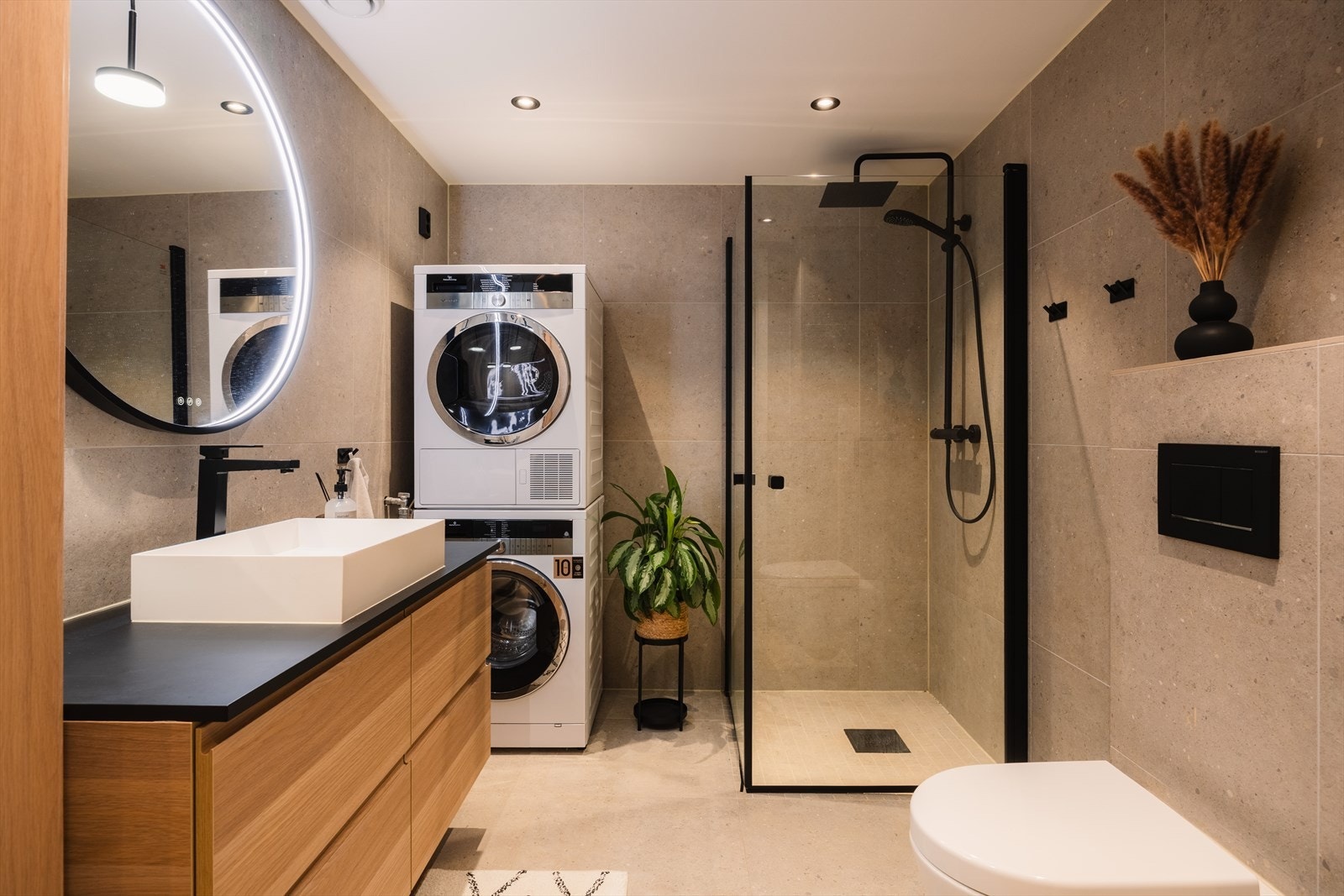 Stilrent og romslig bad med moderne fliser og praktisk opplegg for vaskesøyle. Galleribilde