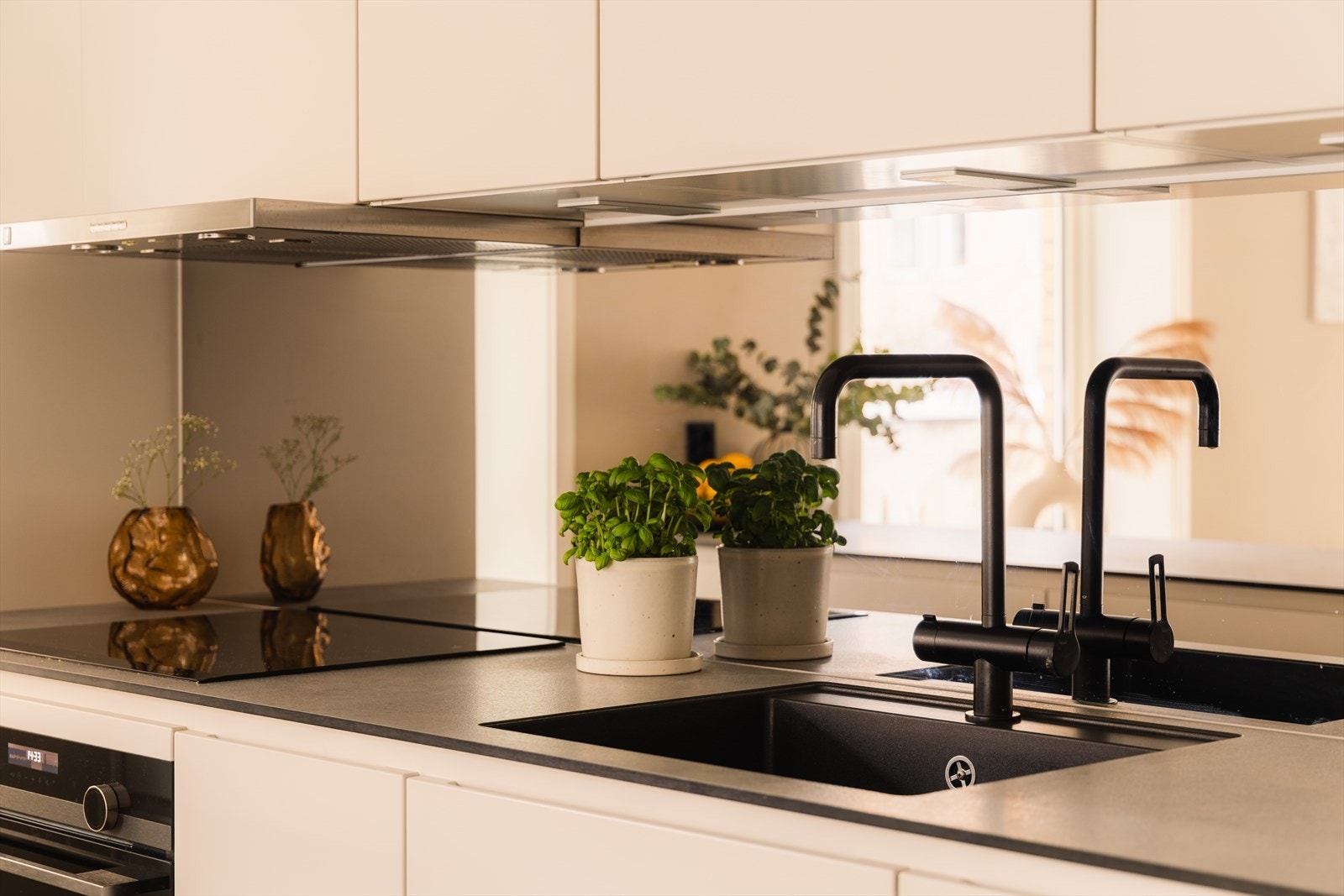 Moderne detaljer med lekker kontrast - sort armatur, underlimt vask og integrert platetopp. Galleribilde