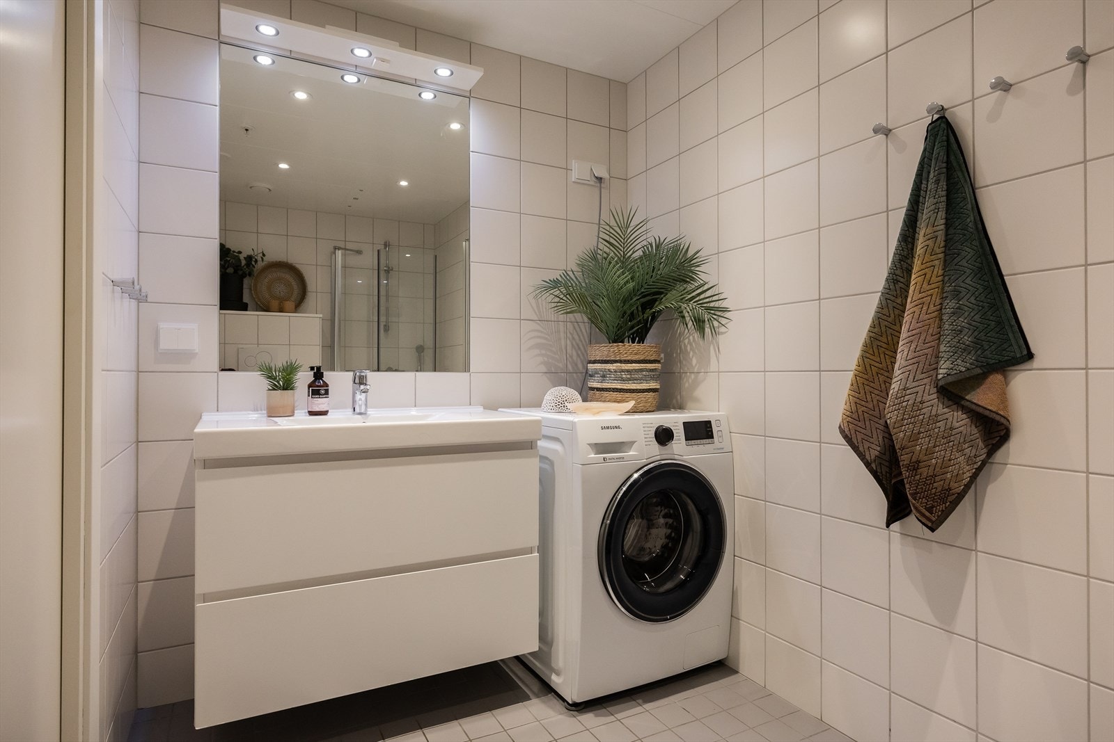 Badet er ellers utstyrt med servantskap, innfelt speil på vegg, dusjhjørne med innfellbare dusjdører, veggmontert wc, mekanisk avtrekk, rørfordelingsskap og stoppekran. Galleribilde