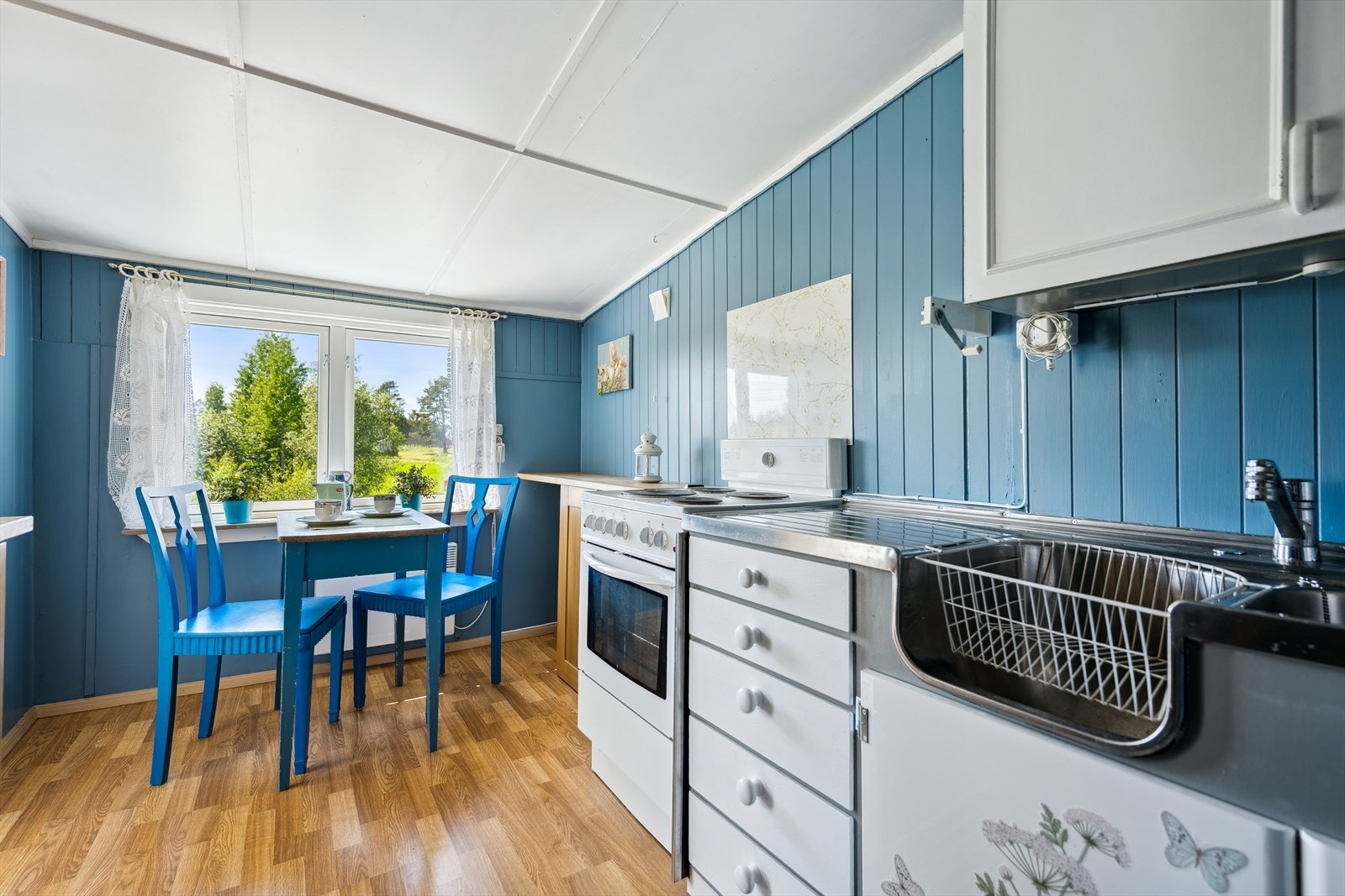 Kjøkkenet har klassisk hyttestil med malte panelvegger og praktisk arbeidsflate. Galleribilde