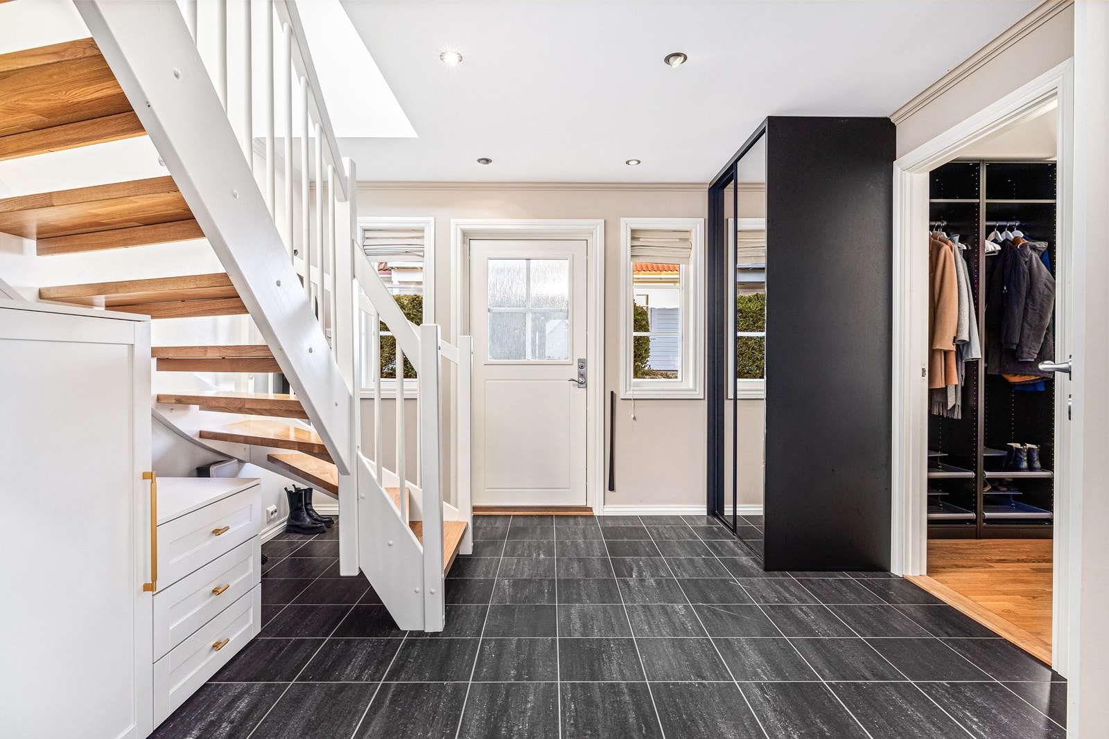 Flislagt gang/entré med varmekabler i gulv og eiketrapp opp til boligens 2. etasje. Galleribilde