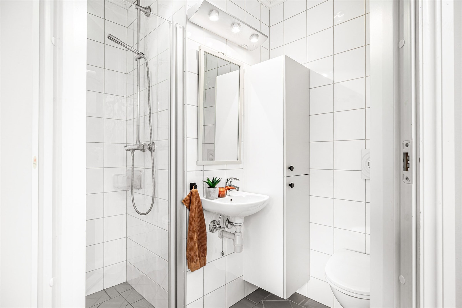 Flislagt bad med servant, høyskap, dusjnisje og toalett. Galleribilde