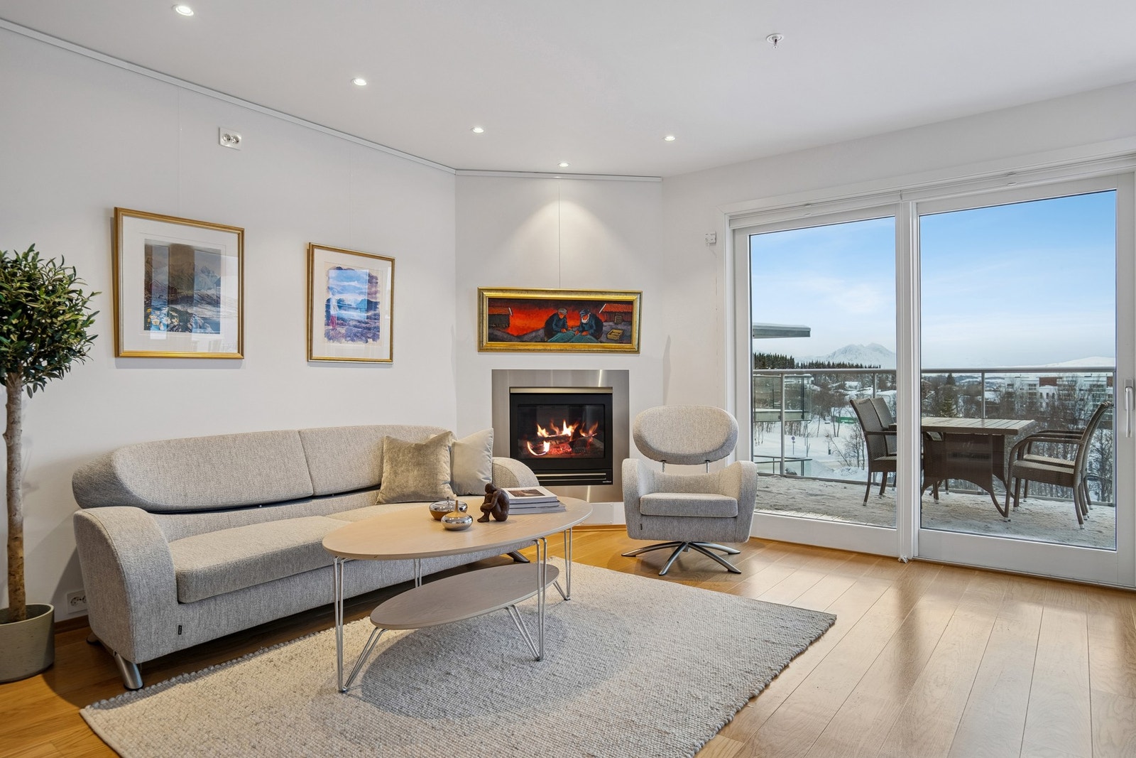 Stuen har lyse overflater og belysning med spotter. Store vinduer slipper inn rikelig med naturlig lys Galleribilde