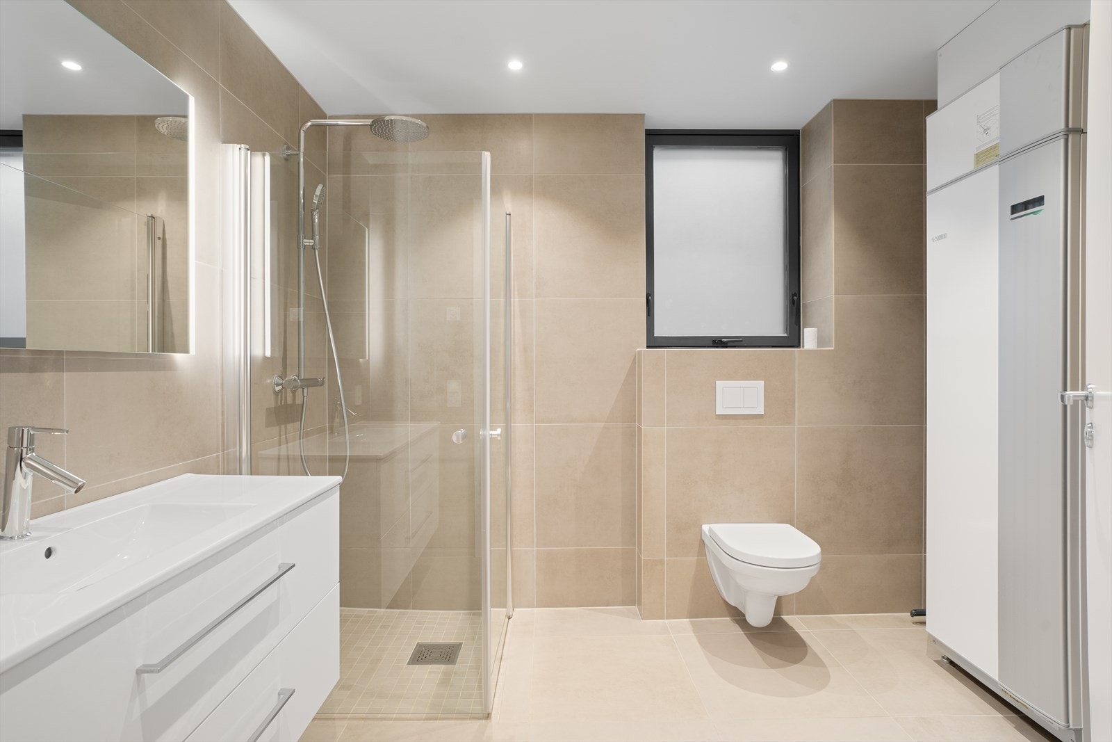 Lekkert bad/vaskerom med store, delikate fliser på vegger og gulv. Galleribilde