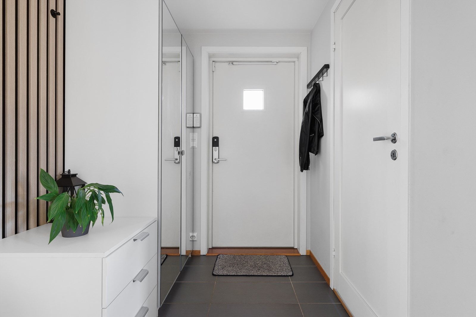 Delikat og lyst inngangsparti med garderobeskap med speil Galleribilde