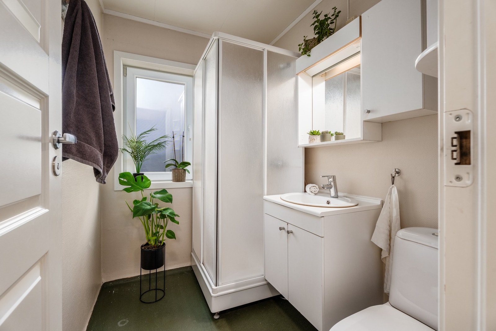 Lyst baderom med toalett, baderomsinnredning og dusjkabinett. Galleribilde