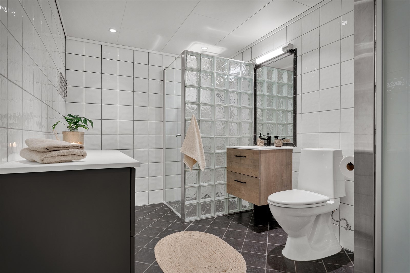 - Lyst og fint bad med gulvmontert toalett, benkeskap med servant, dusjvegg med glassdør, opplegg for vaskemaskin og varmtvannsbereder - Galleribilde