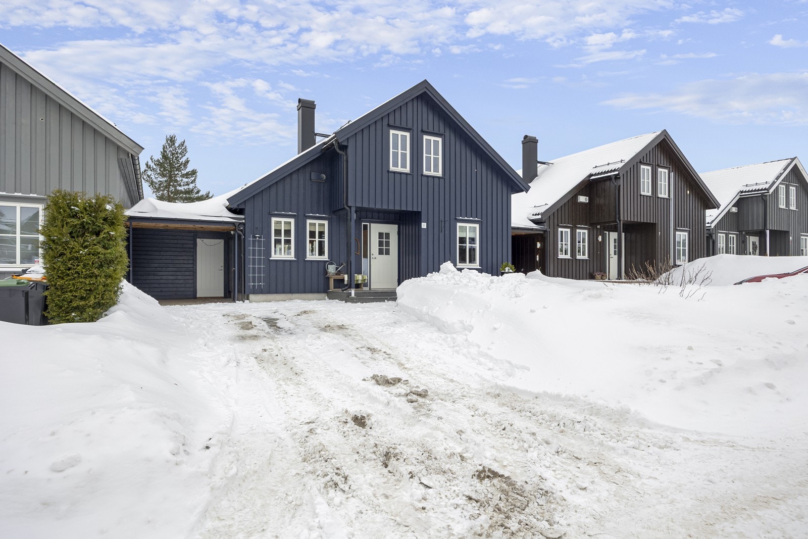 God plass til parkering på egen tomt. Foran huset er det plen med hekk og diverse bærbusker. Galleribilde