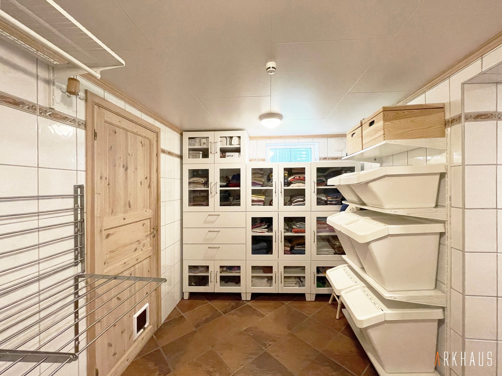 Stort vaskerom med veggmontert tørkestativ, innebygde skap og kurver på veggmonterte hyller Galleribilde