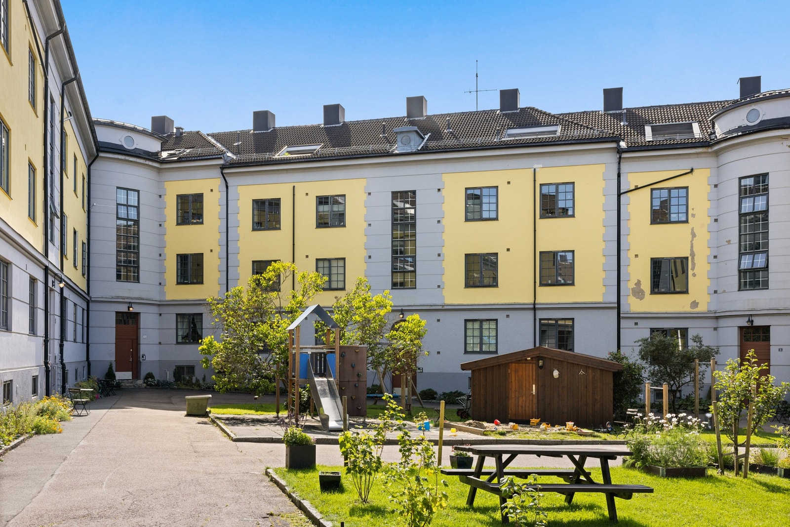 Bakgården er nydelig på sommerhalvåret. Den er pent opparbeidet med lekeplass, sittebenker, asfalterte veier og beplantning. Galleribilde