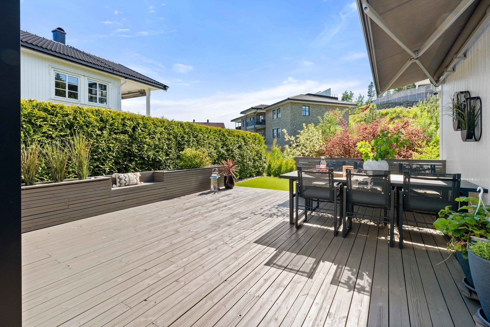 God plass til spisegruppe omkranset med plantekasser og sittebenk. Galleribilde