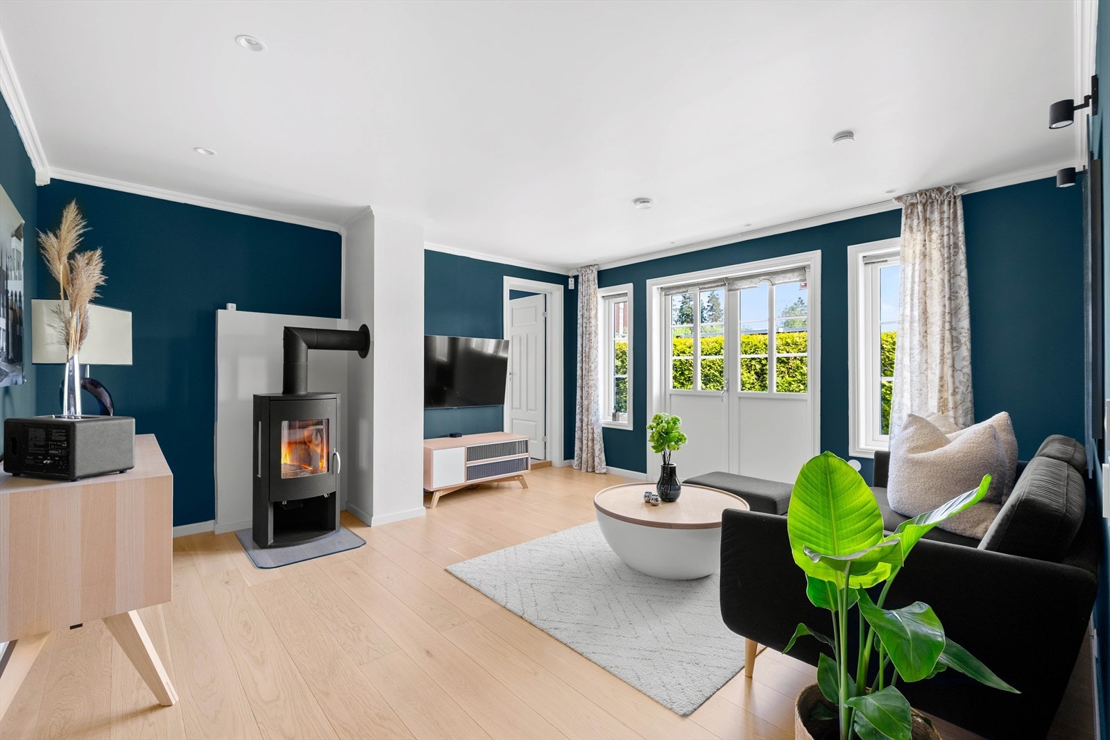 Koselig TV-stue med peis og direkte utgang til hagen. Nyt varme kvelder foran peisen eller ta steget ut i den grønne hagen for frisk luft og avslapning! Galleribilde