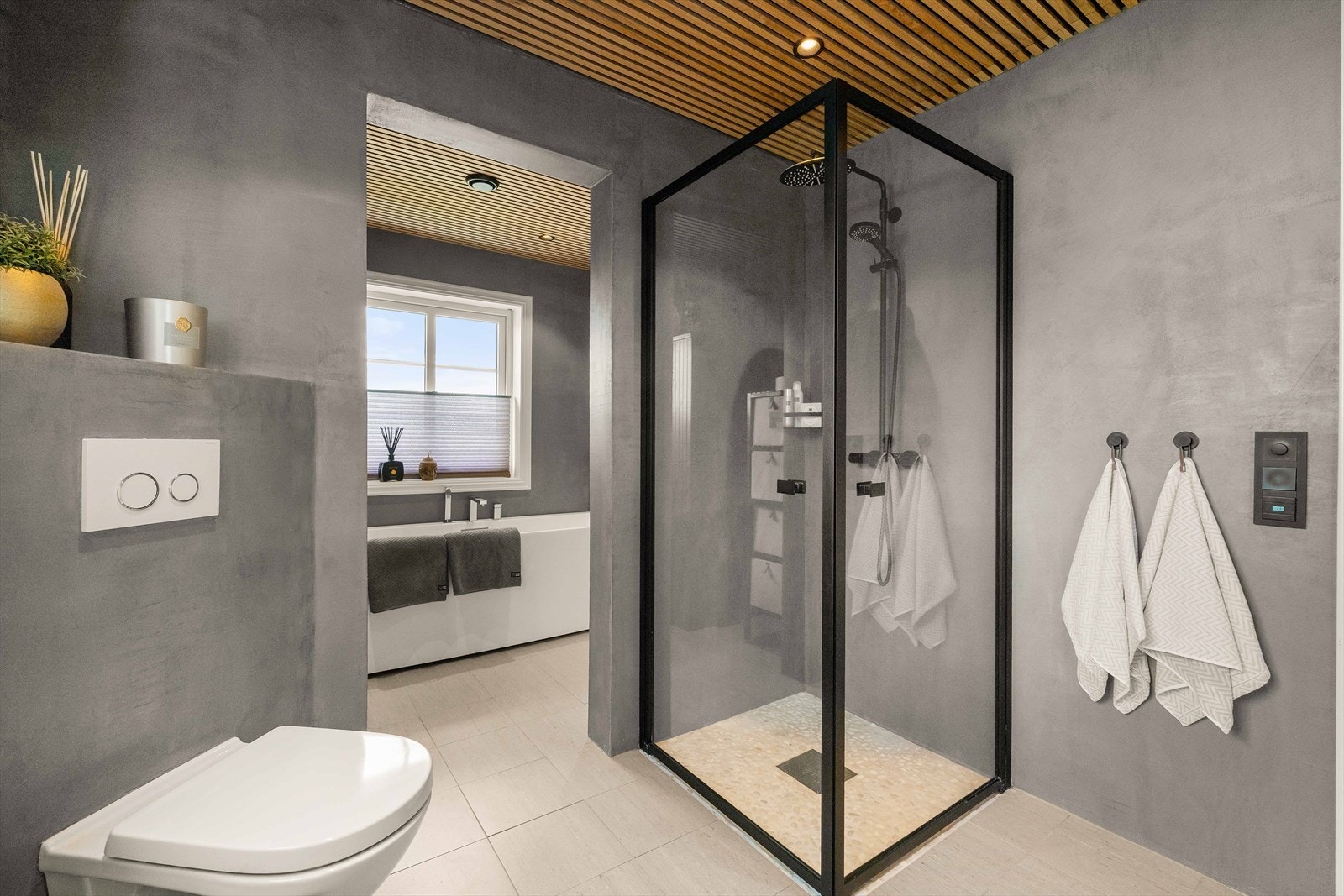 Innredet med dusj, vegghengt toalett, badekar og servant med møblement og belysning. Galleribilde