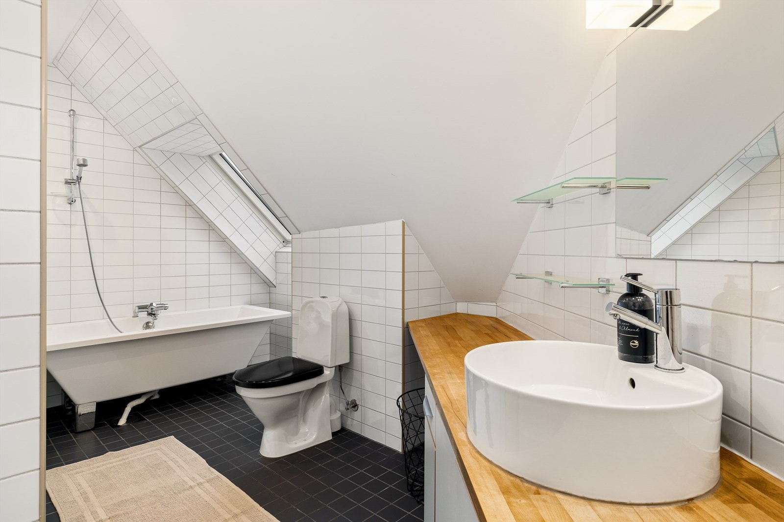 Badet er godt utstyrt med WC, badekar med dusj og en stilfull servant med innredning - alt du trenger for komfort og funksjonalitet. Galleribilde