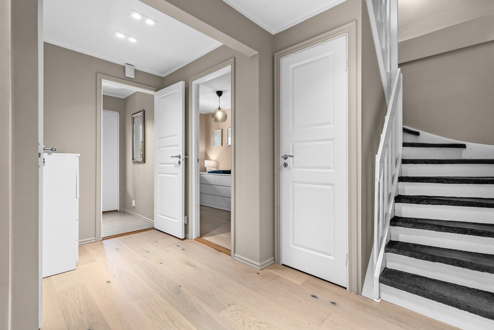 Gangen har malte, slette vegger i en moderne beige farge og downlights i himling. Videre inn i gangen er det adkomst til to soverom, bad, vaskerom og bod under trapp. Galleribilde