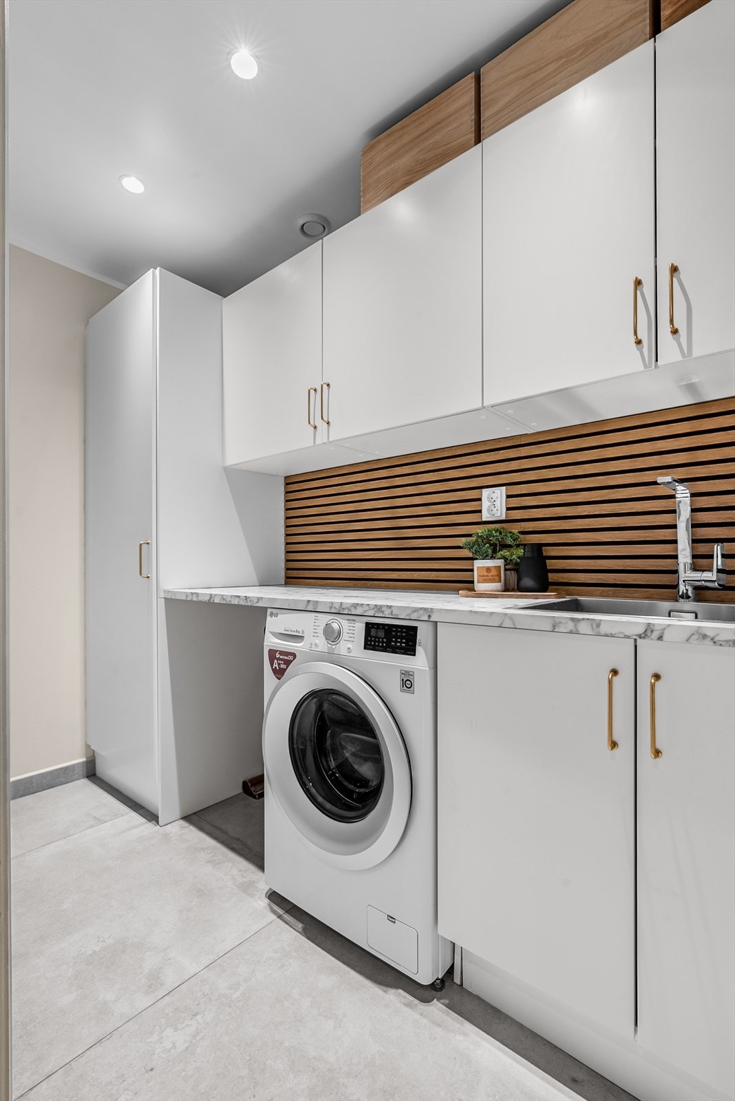 Praktisk vaskerom med opplegg for vaskemaskin, tørketrommel og godt med skap- og benkeplass. Galleribilde