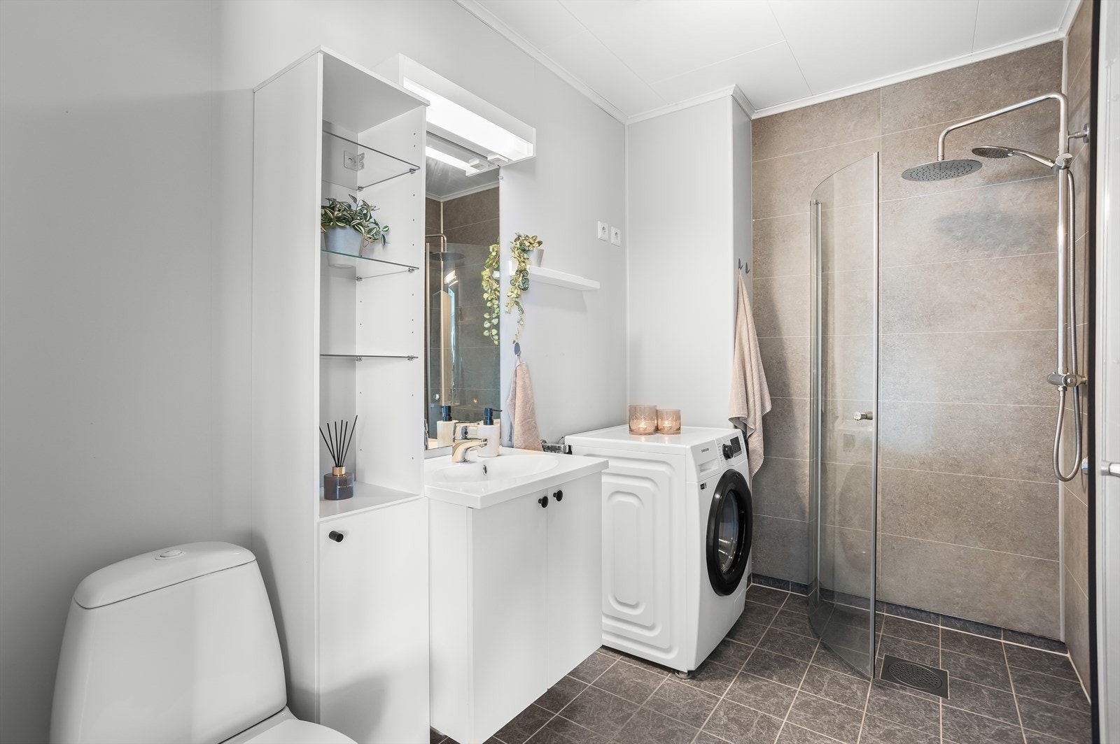 Badet har flislagt gulv med gulvvarme, våtromsplater på veggene og opplegg for vaskemaskin. Galleribilde