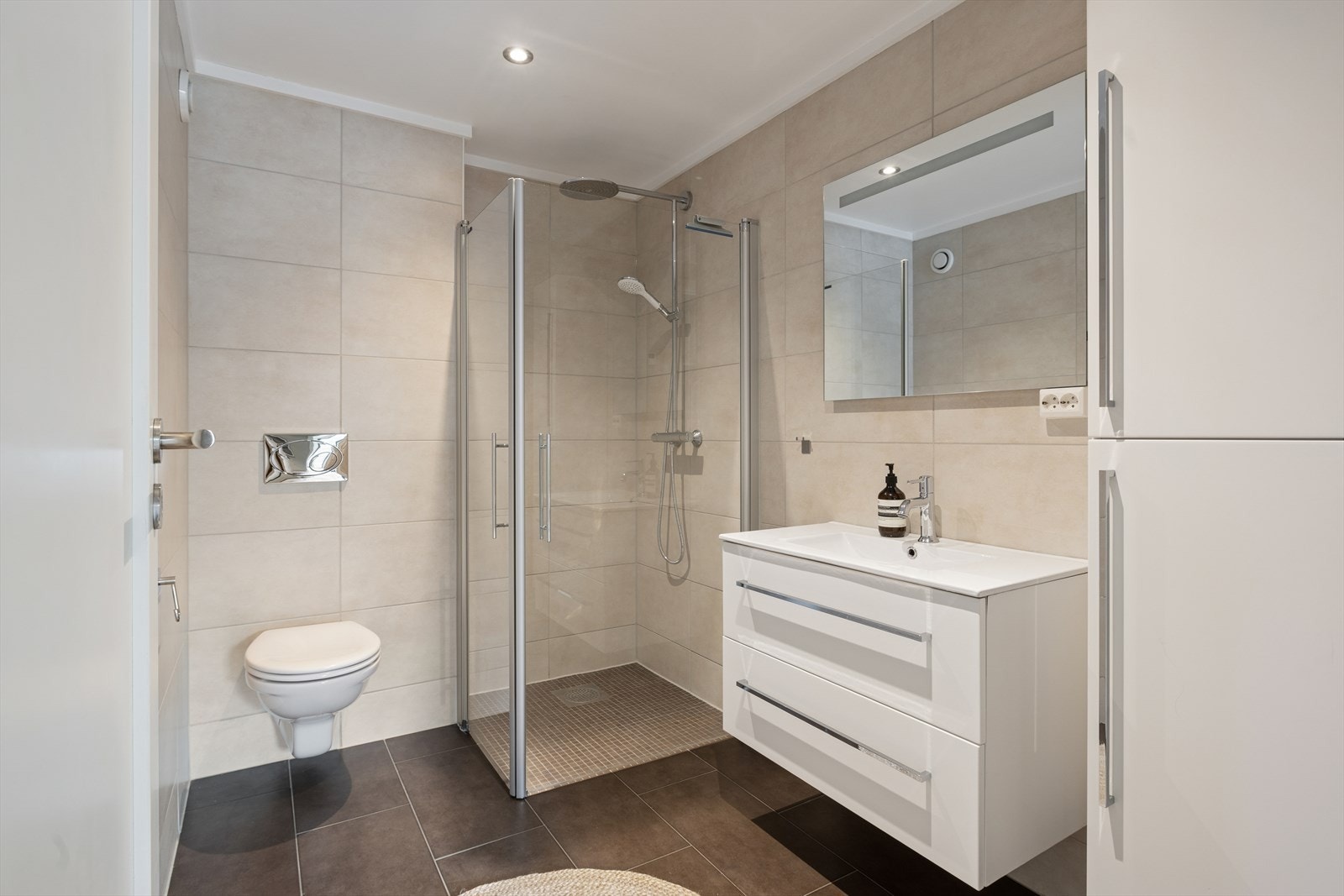 Badet er fra byggeåret og fremstår som et solid og velholdt våtrom med flislagte vegger og gulv. I dusjsonen er gulvet senket og har tilfredsstillende fall mot sluk for effektiv vannavrenning. Galleribilde