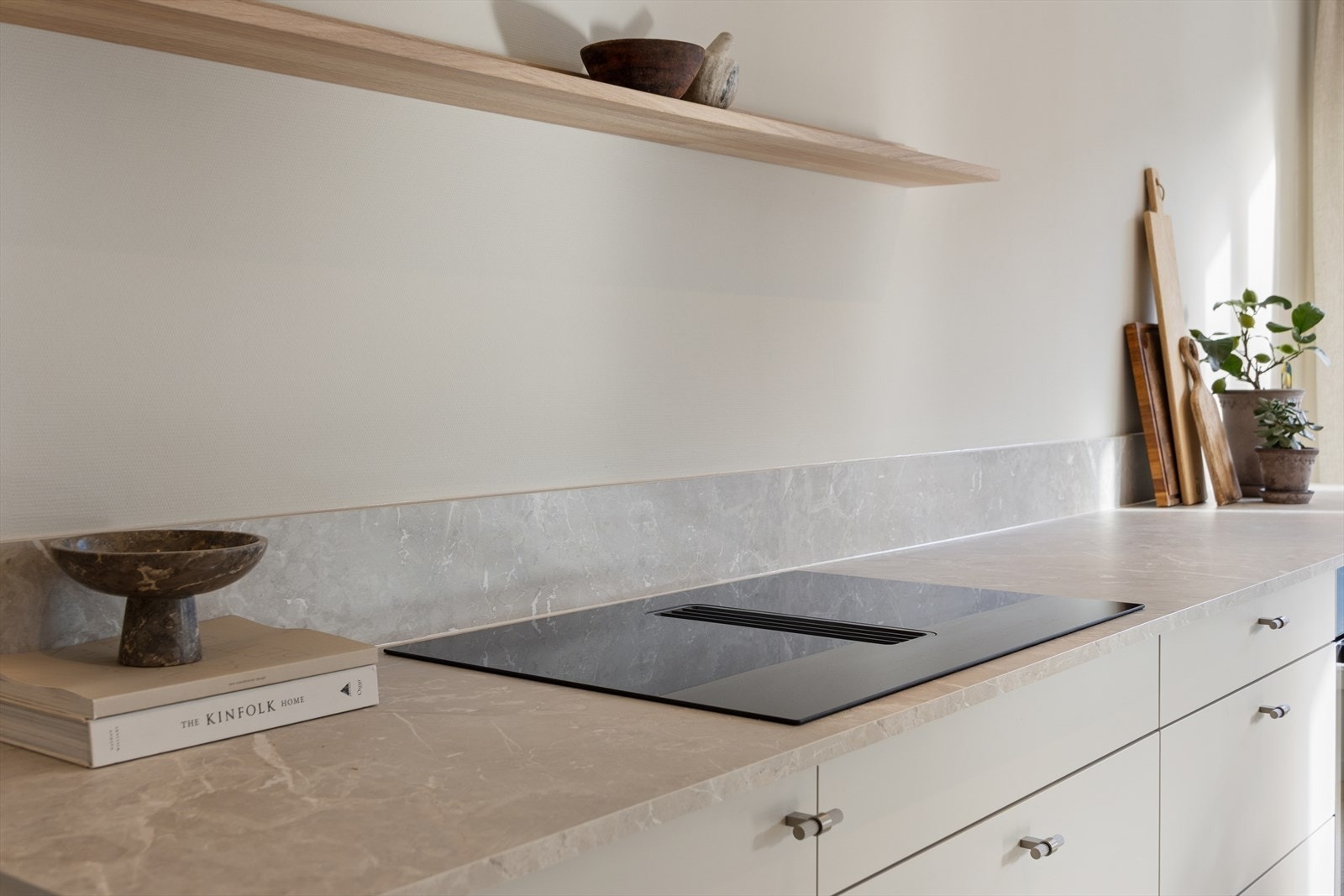 Kjøkkenet er oppgradert med ny benkeplate i et lekkert og tidsriktig materiale, som både løfter uttrykket og gir et slitesterkt arbeidsområde. Det er installert en moderne platetopp med integrert bordvifte, som trekker matos effektivt ned i benken. Galleribilde