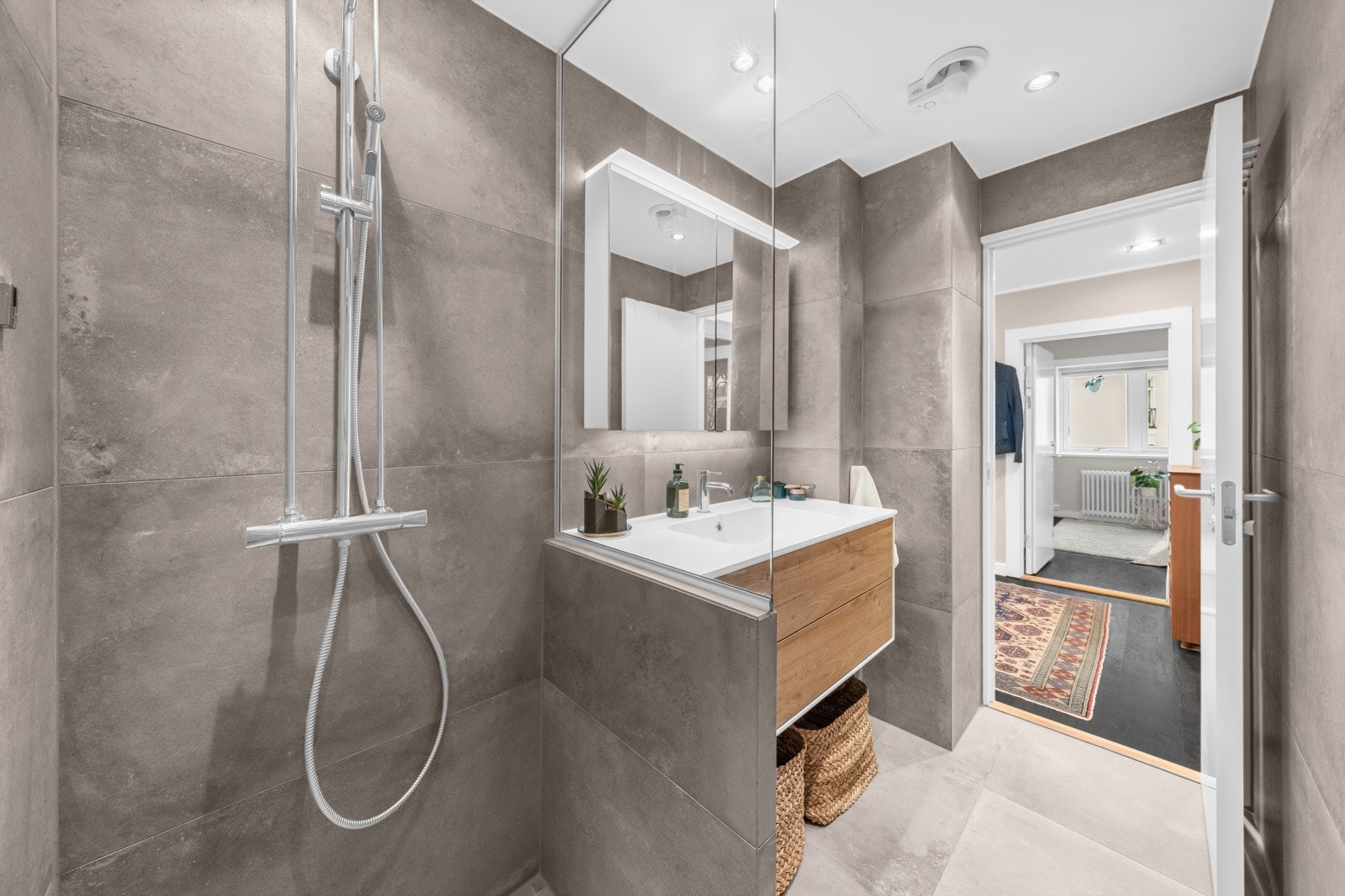 Dusjhjørnet er naturlig avskilt med fastmontert glassvegg, og to-greps armatur påkoblet hånddusj og regndusj. Galleribilde