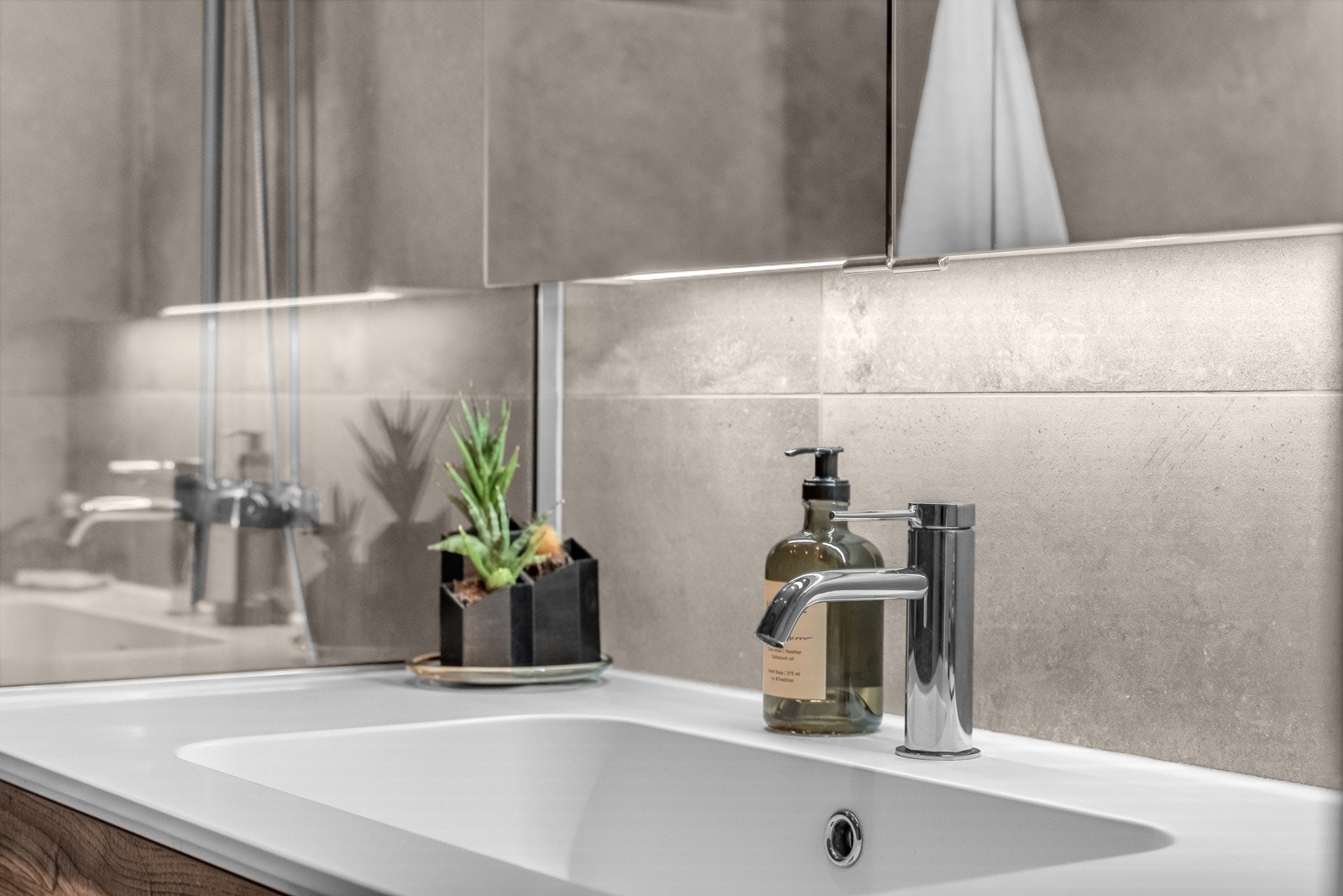 Badet er innredet med vegghengt servantskap med overhengt speilskap med belysning. Galleribilde