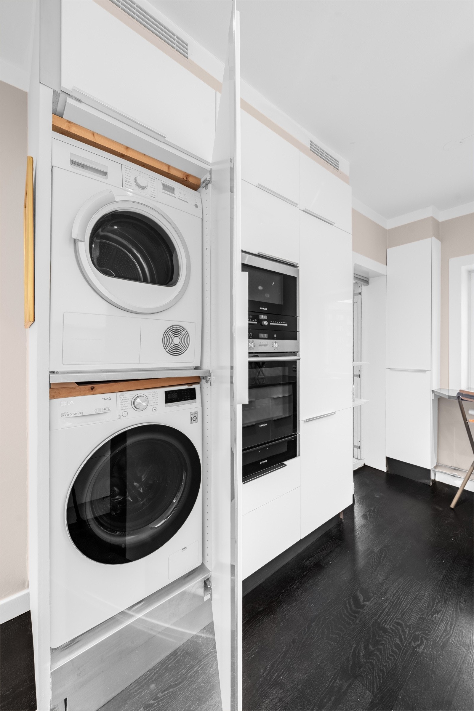 Vaskemaskin og tørketrommel er praktisk montert i høyskap på kjøkken. Galleribilde