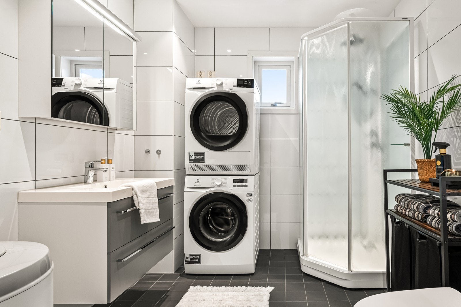 Moderne bad med våtromsplater på veggene, dusjkabinett og opplegg for vaskemaskin. Galleribilde