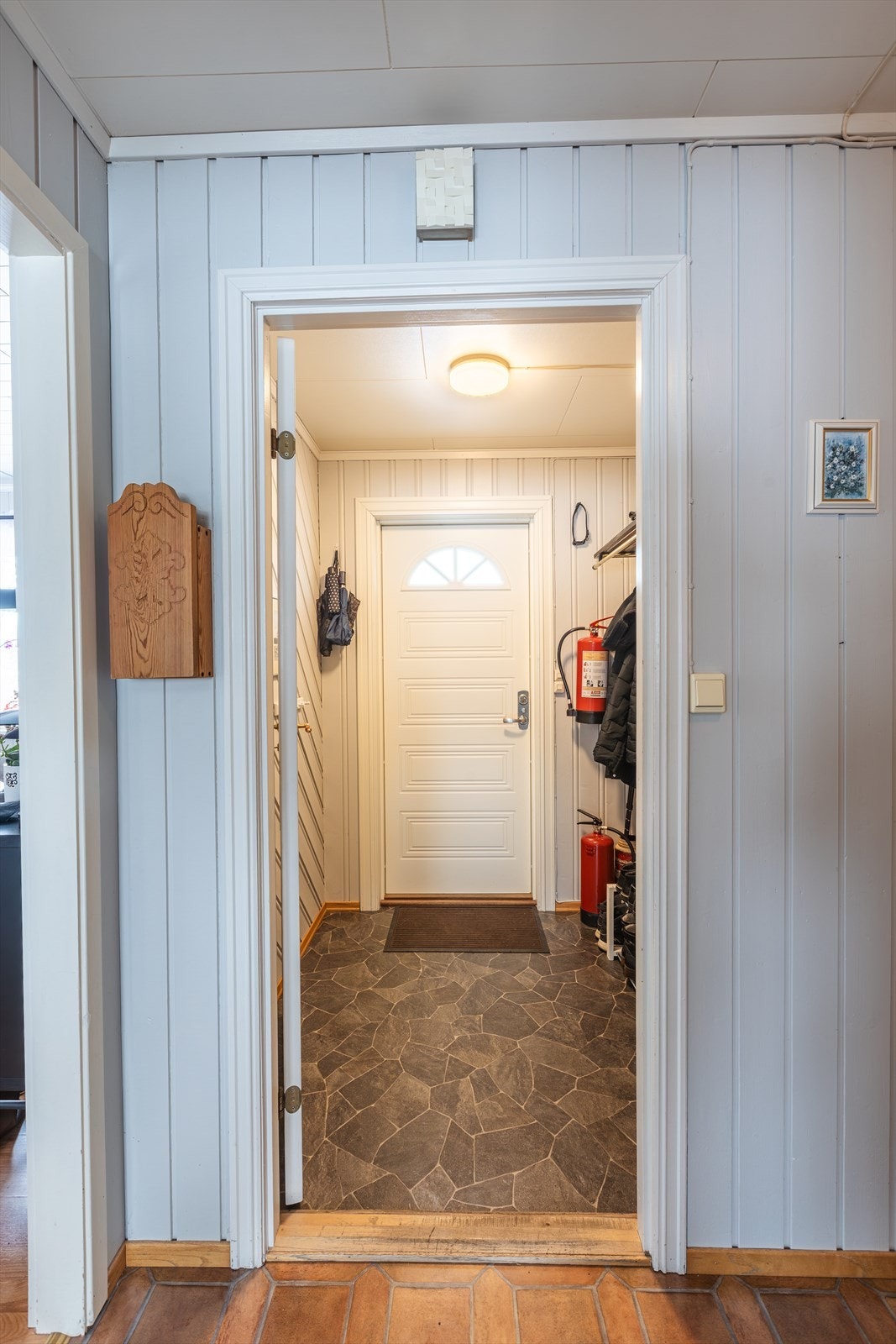 Velkommen inn til et inngangsparti med malt panel på veggene som skaper en stilren overgang til resten av boligen som bærer preg å være godt vedlikeholdt. Galleribilde