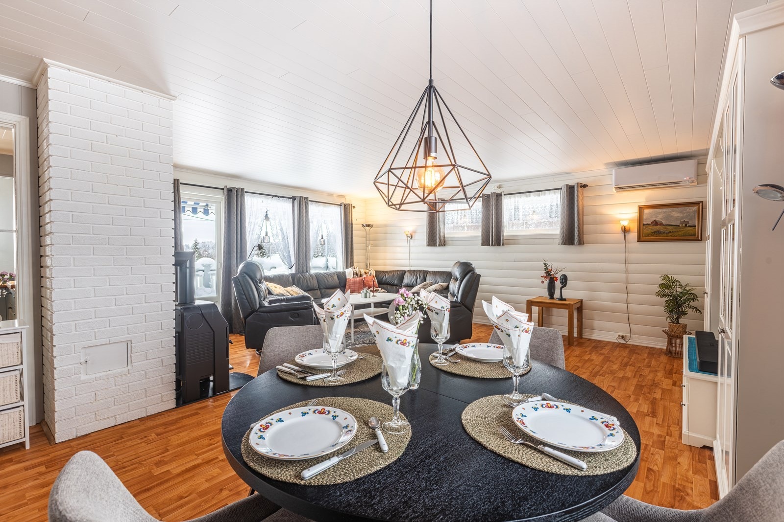 Åpen stue med spiseplass ved store vinduer som gir rikelig med naturlig lys. Stuen har både peisovn og varmepumpe. Galleribilde