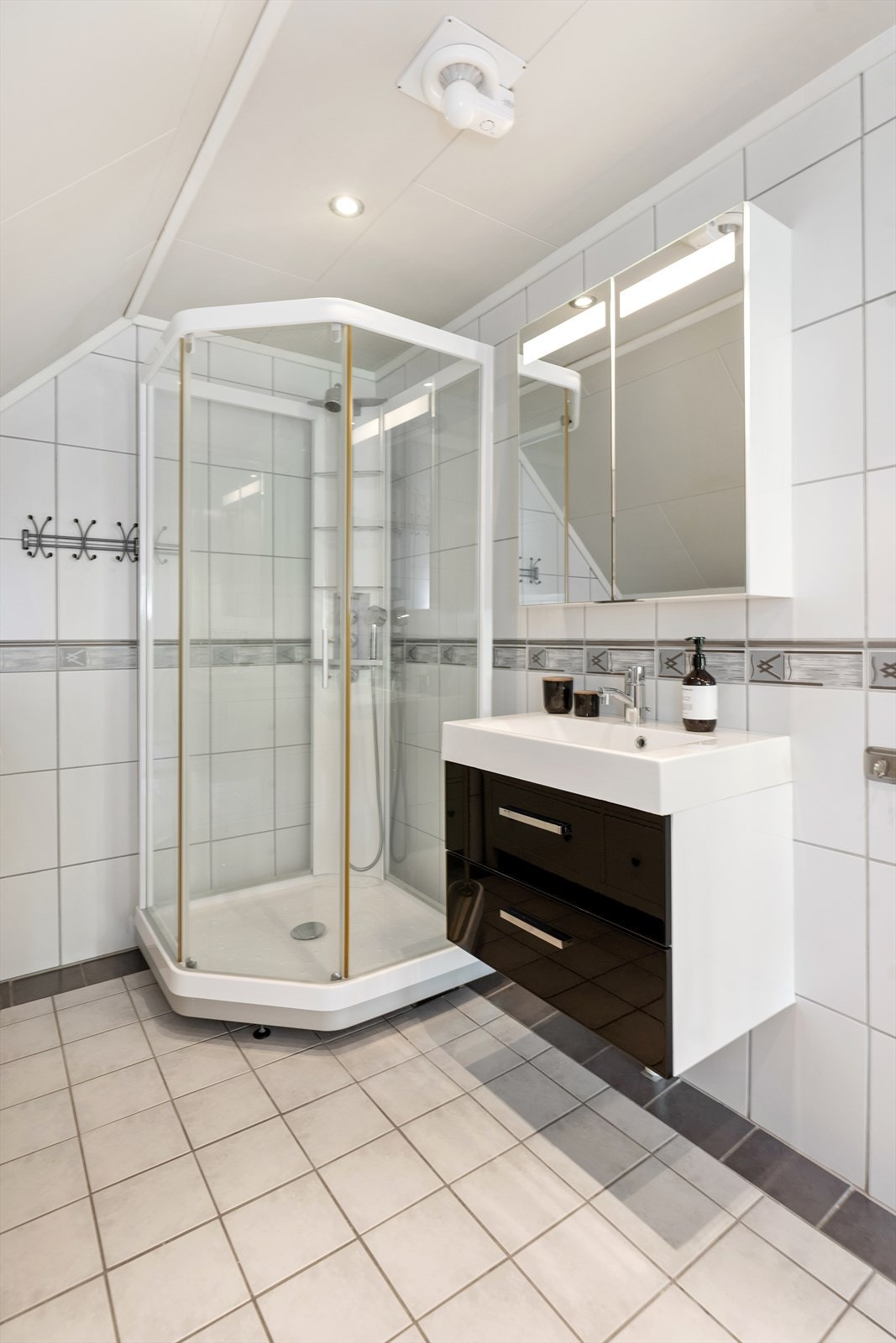 Badet er utstyrt med toalett, servant med skuffer og dusjkabinett. Galleribilde