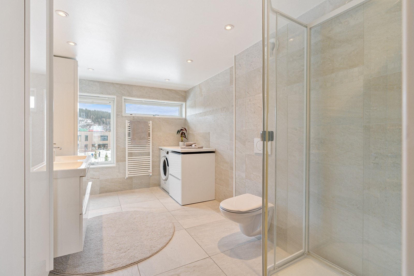 Lekkert baderom på 8,5 kvm med fliser på gulv og vegg i nøytrale farger. Det er selvfølgelig varme i gulv og led downlights i himling. Installert automatisk avtrekksvifte. Galleribilde