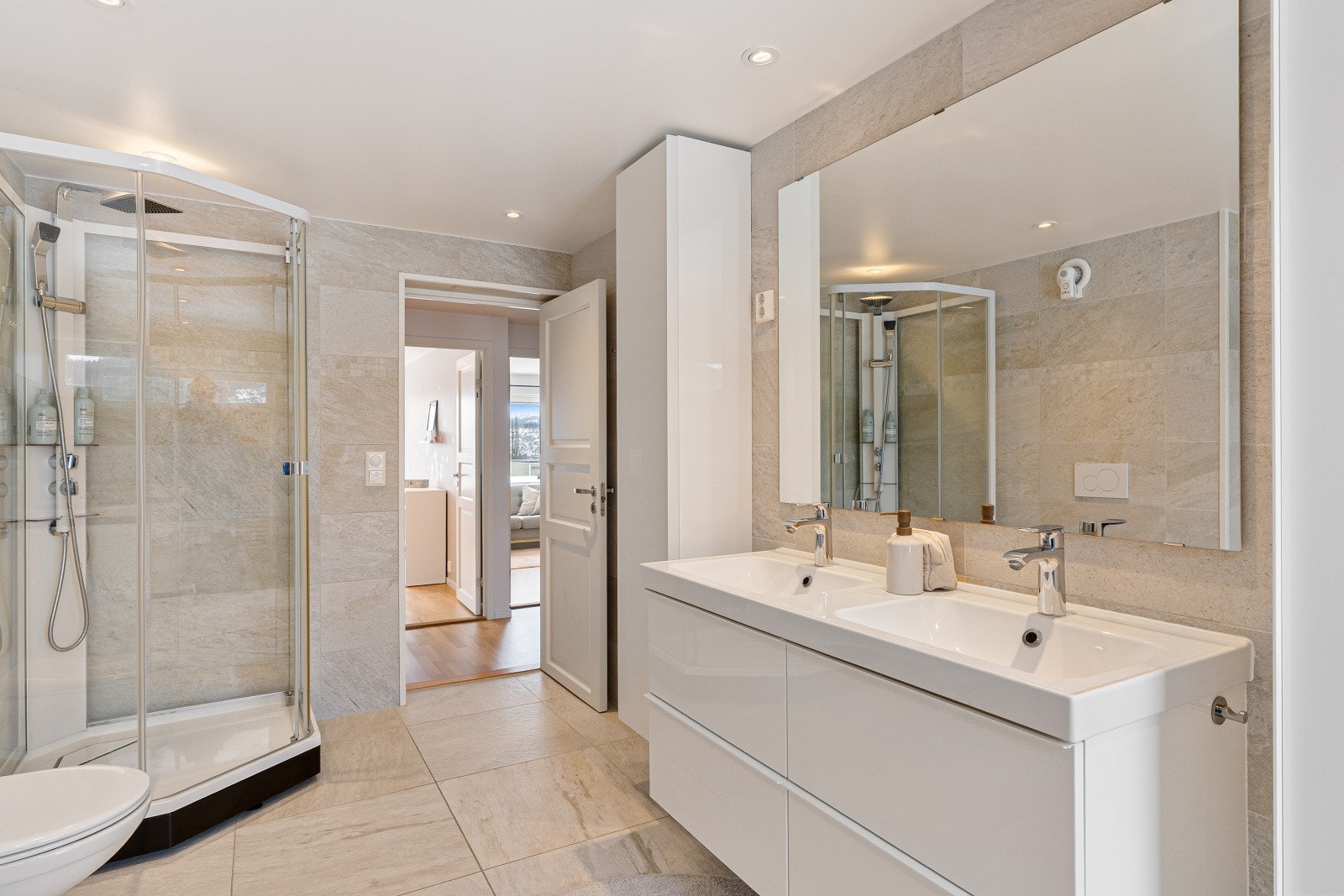 Stort speil og godt med oppbevaringsplass for toalettartikler i høyskap og skuffer. Dusjkabinett fra Porsgrunn og vegghengt toalett fra Geberit. Galleribilde