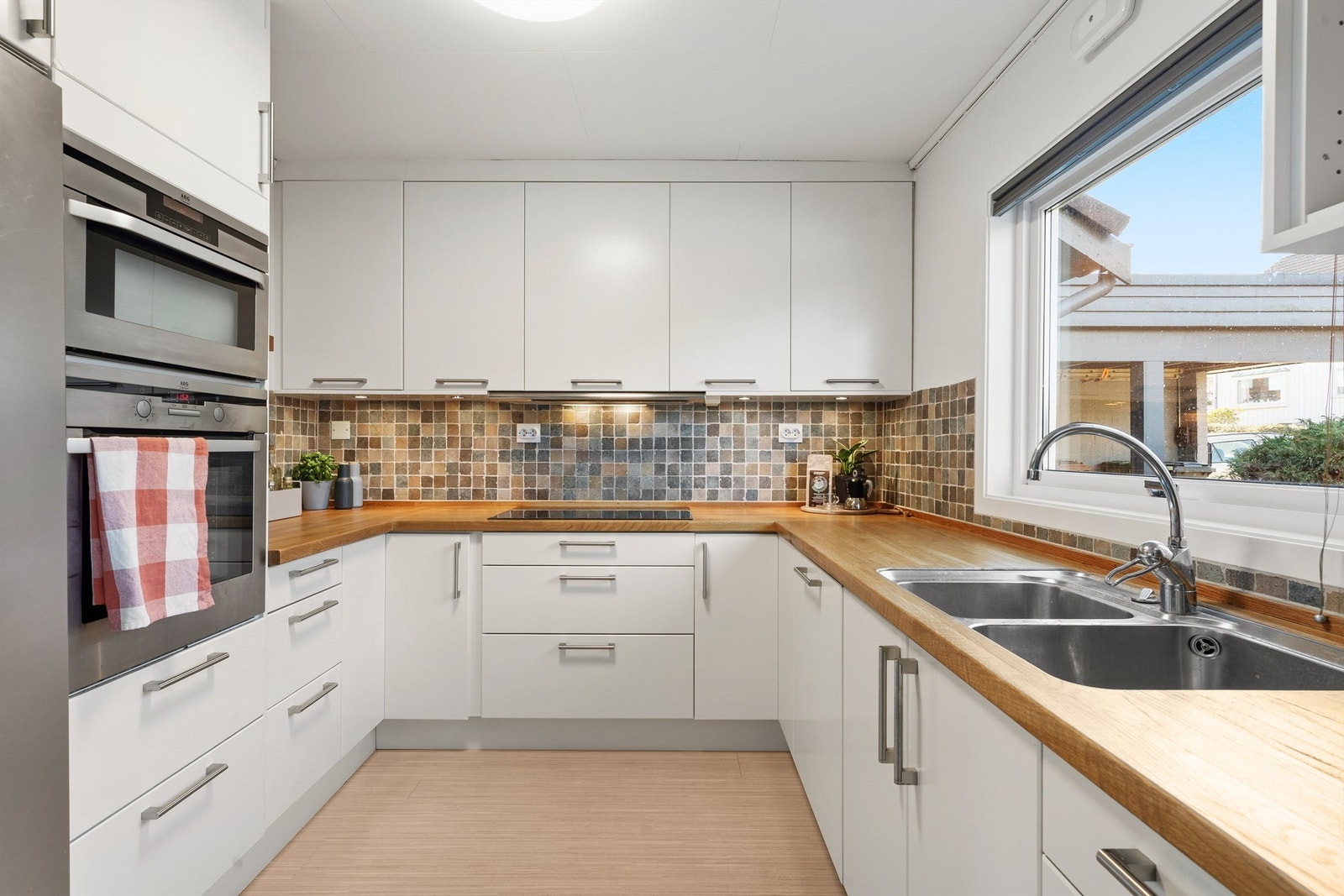 Tidløs og fin innredning fra 2008 i hvitt. Heltre benkeplate og spotter under overskap. Kjøkkenet har en praktisk og god utforming, som gir bra med oppbevaring i skuffer og skap, i tillegg til god benkeplass. Galleribilde