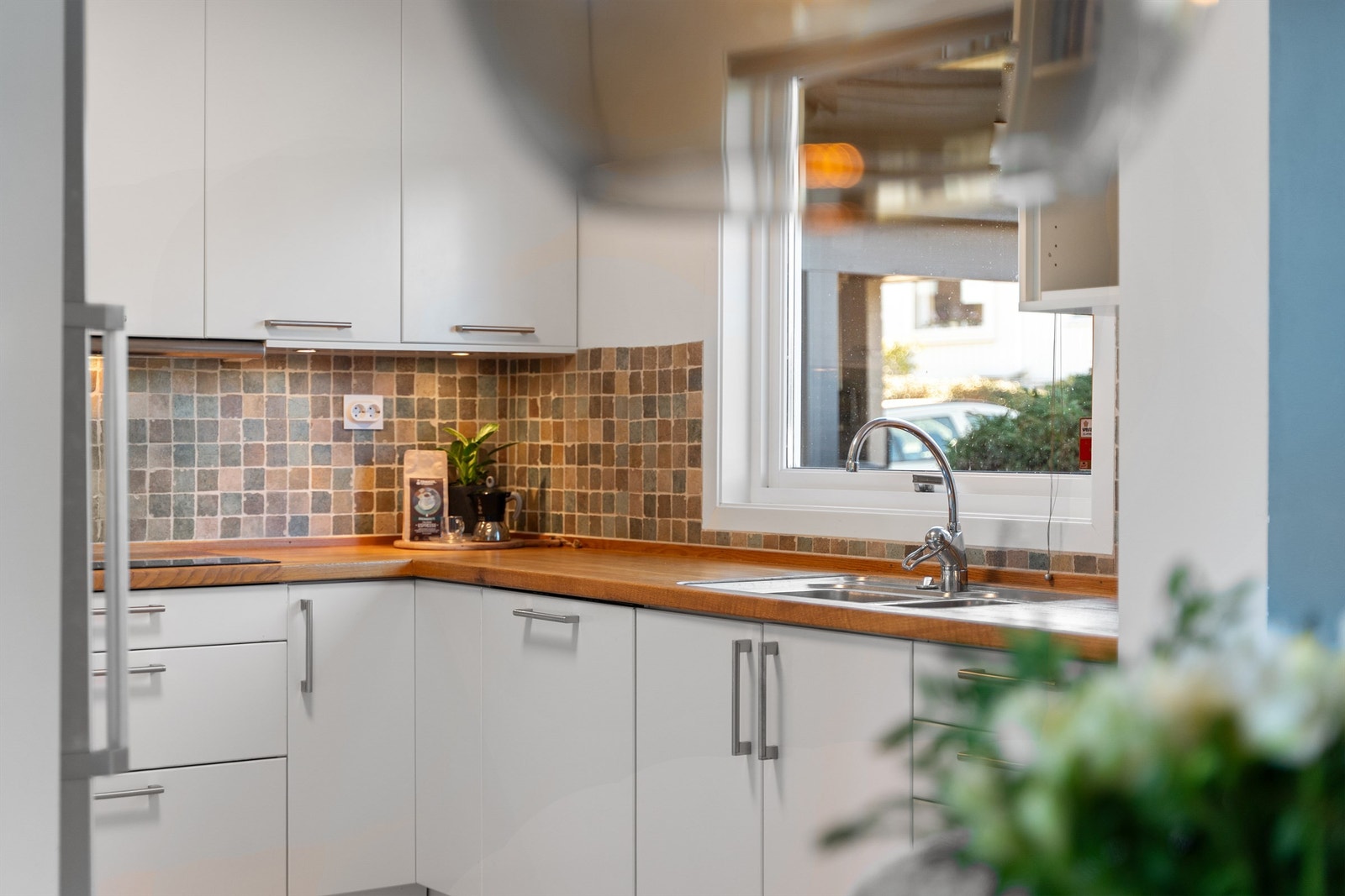 Fliser på vegg mellom overskap og benk, i tillegg til stort vindu over benk som gir lysinnslipp og utsikt mot terrasse og inngangsparti. Galleribilde