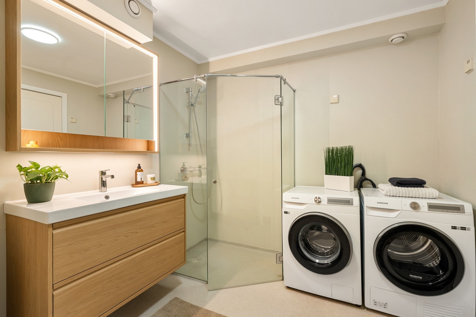 Rommet har belegg på gulv med varmekabler, vegghengt toalett, dusjhjørne med glassvegger og opplegg for vaskemaskin/ tørketrommel. Galleribilde