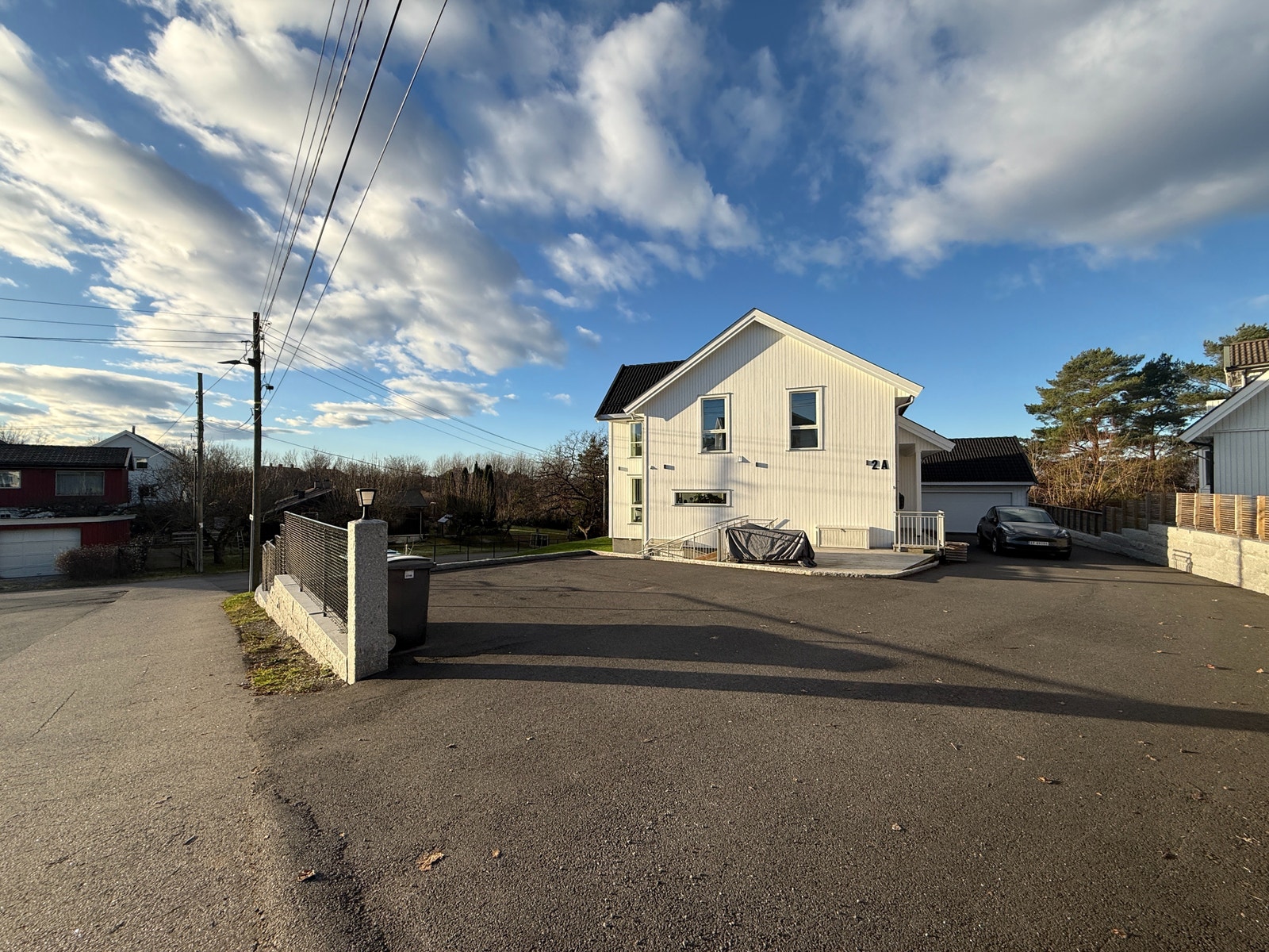 Inngangsparti og parkeringsplass foran boligen. Asfaltert område med god plass til parkering og enkel adkomst fra vei. Galleribilde