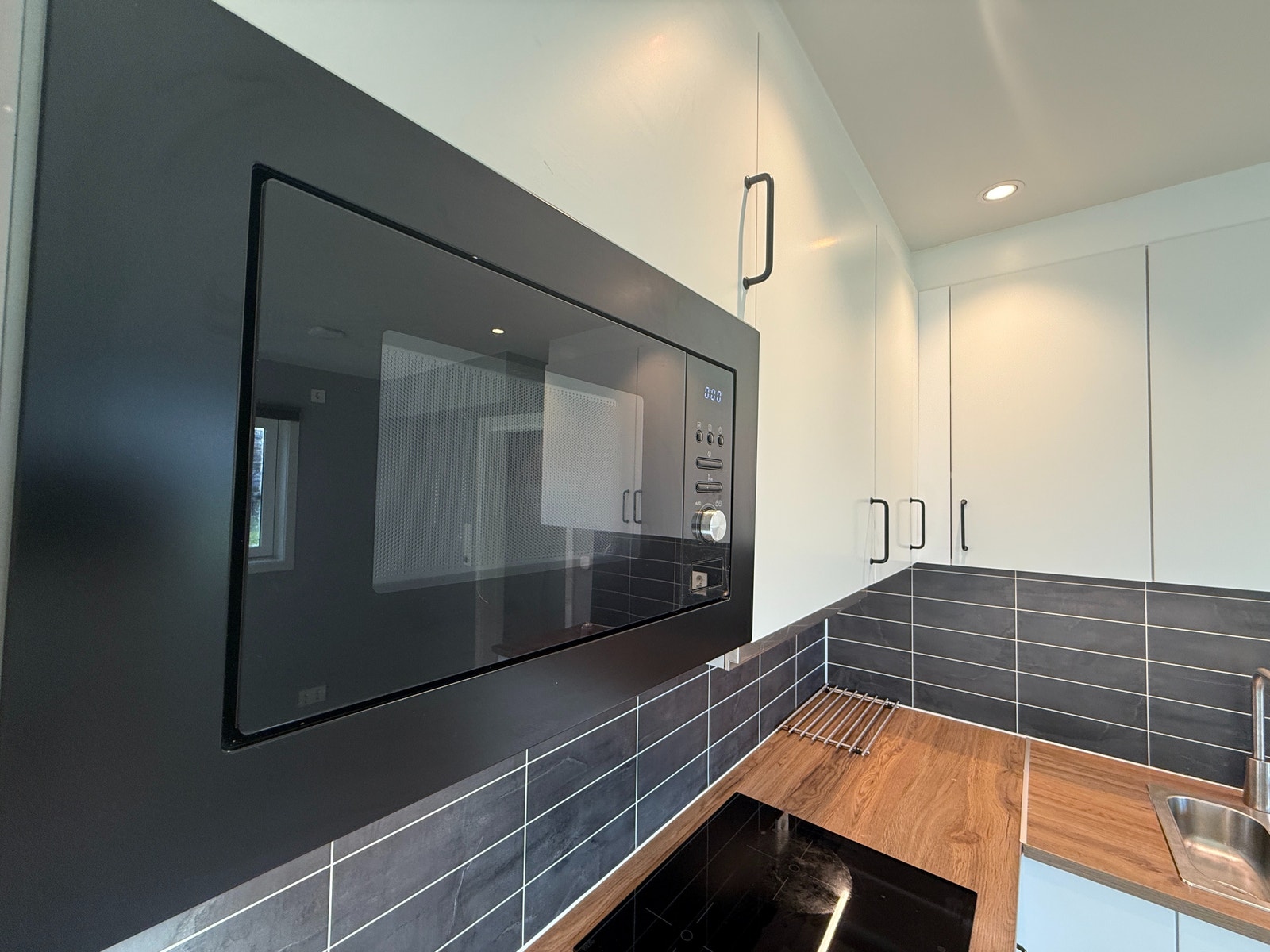 Moderne kjøkken med integrert mikrobølgeovn og god skapplass. Flislagt sprutplate og innfelte spotter gir et lyst og funksjonelt uttrykk. Galleribilde