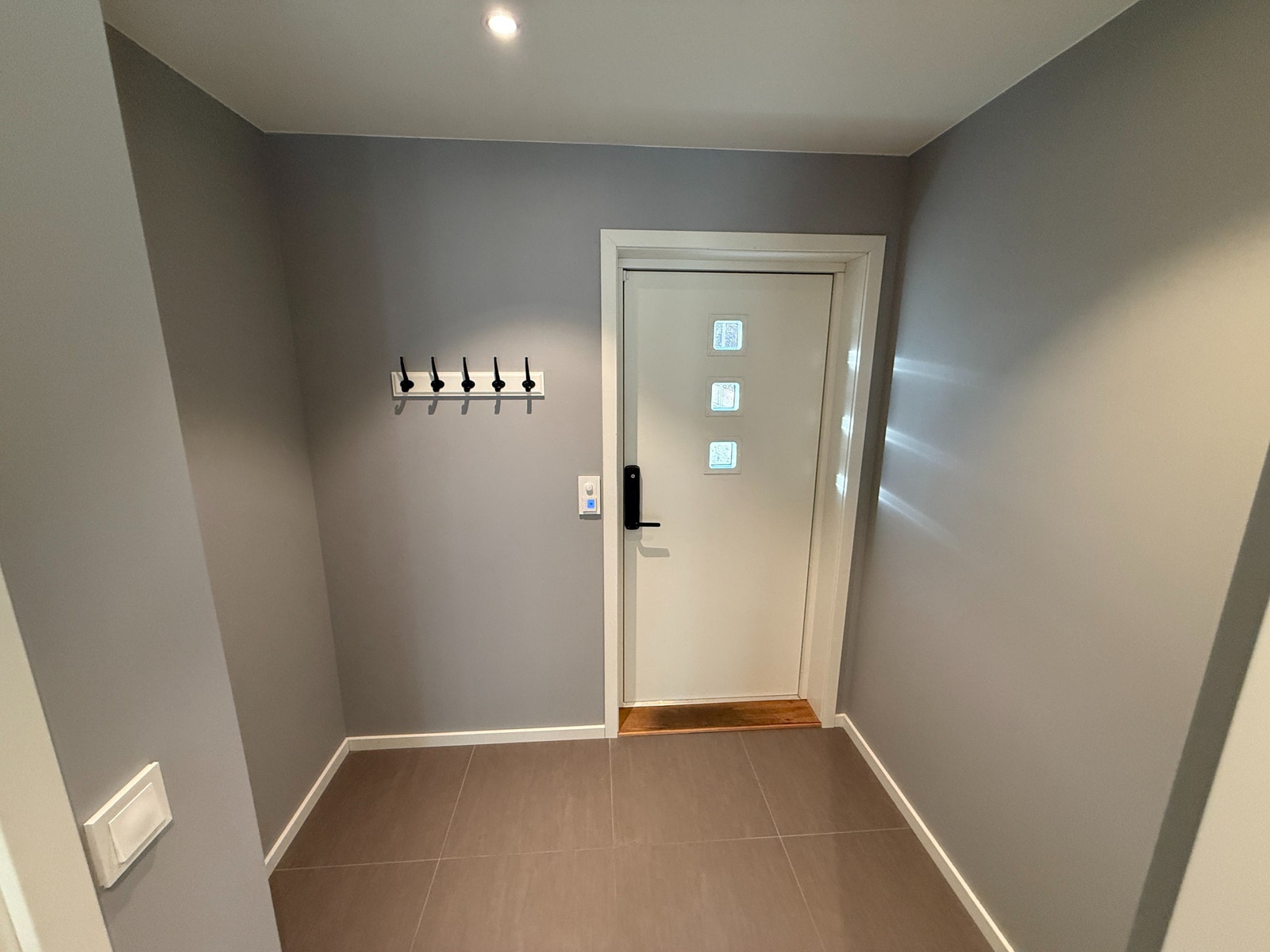 Lys og moderne entré med flislagt gulv, god plass til skohylle og knagger. Privat inngangsdør med vinduer som slipper inn dagslys. Galleribilde