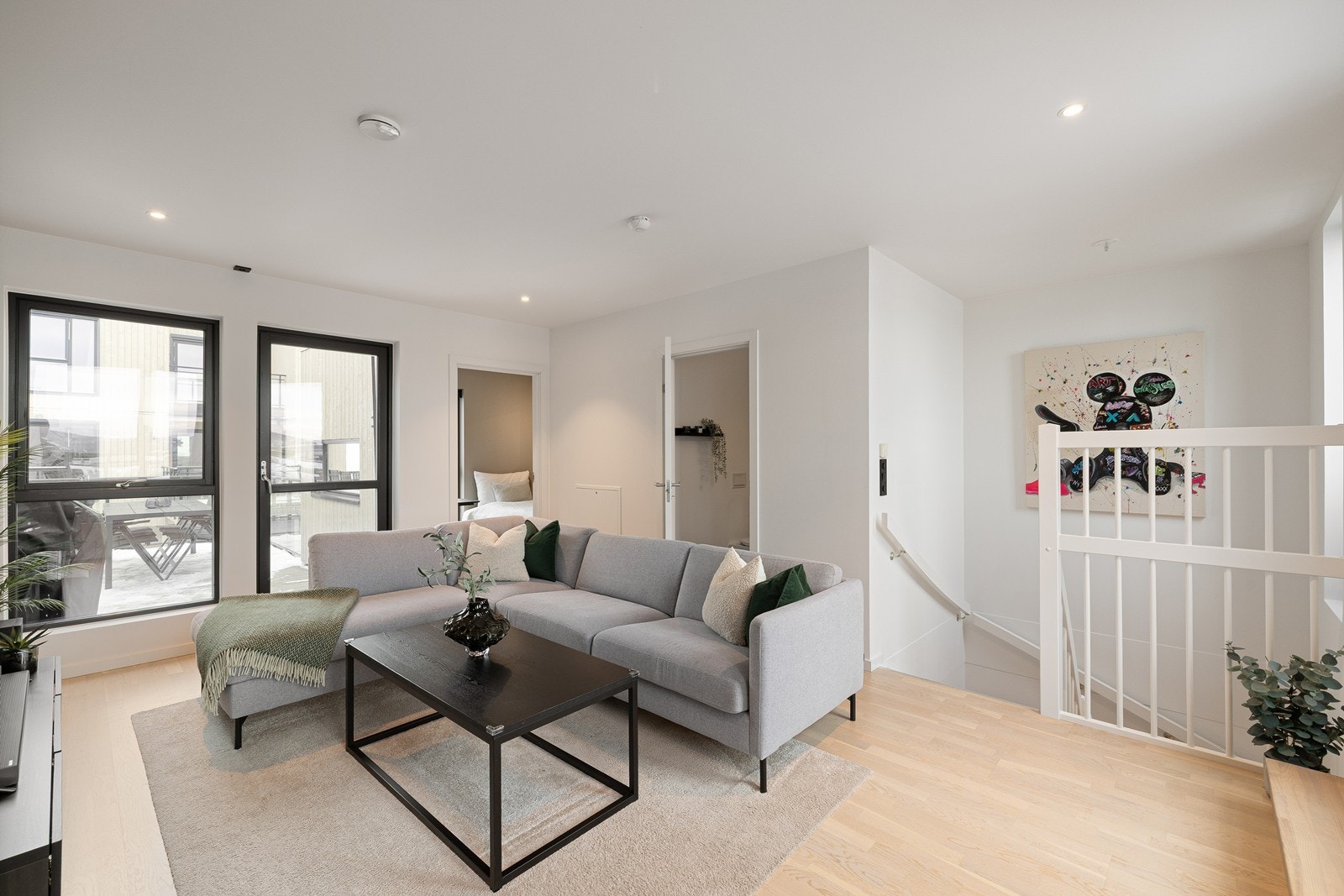 Fra trappen kommer man opp i en lys stue. Rommet har store vindusflater som slipper inn rikelig med naturlig lys fra begge ender. Galleribilde