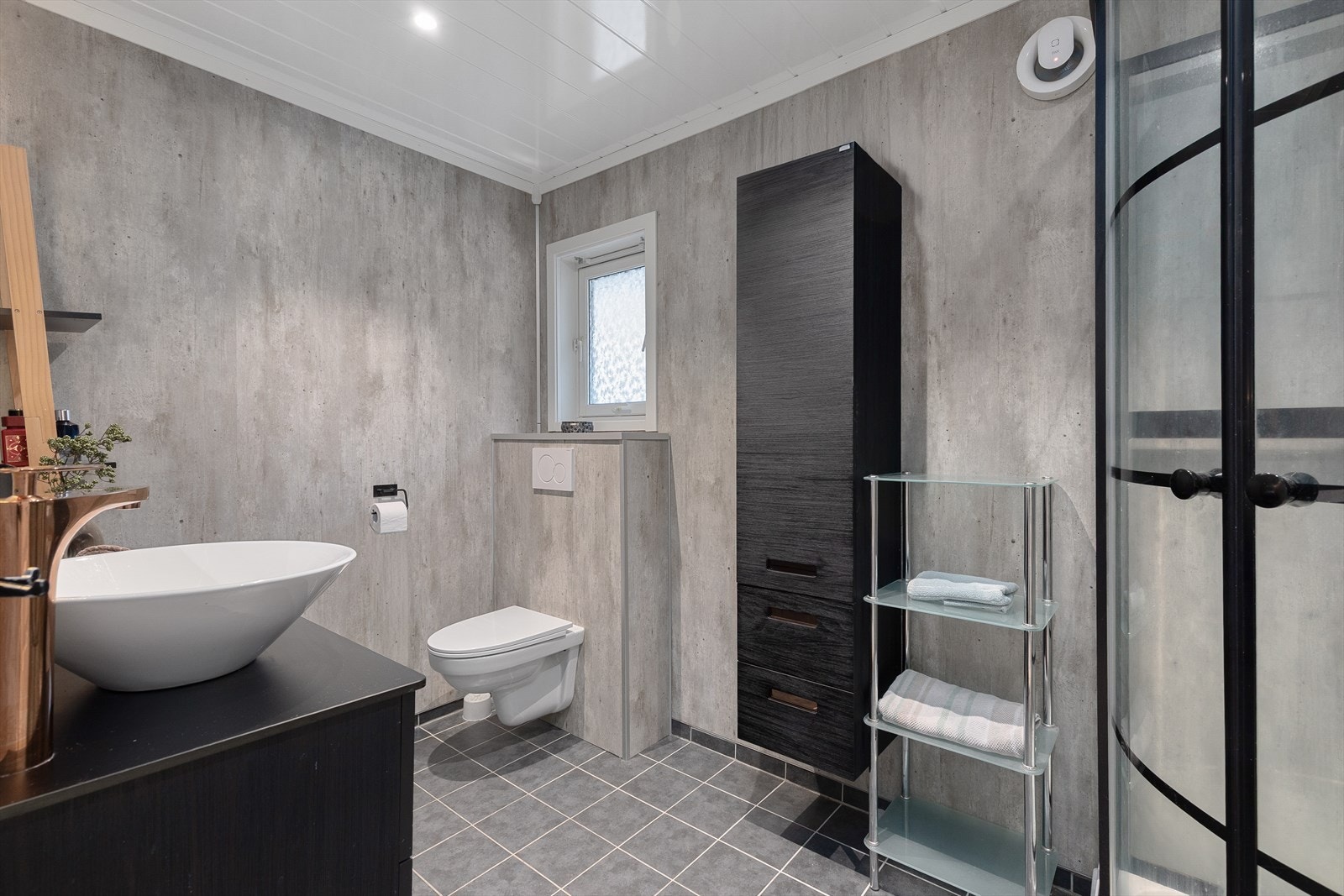 Bad i 1. etasje har baderomsplater på vegg, og fliser på golv. Delikate og moderne baderomsmøbler. Galleribilde