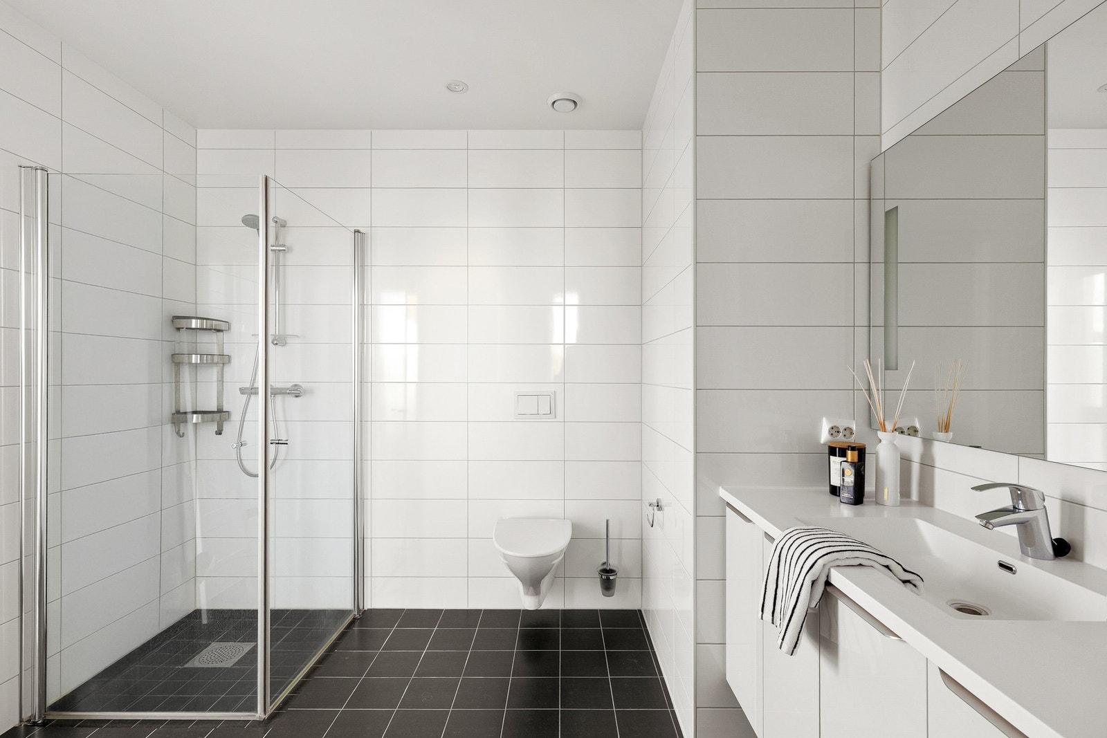 Badet er moderne utført med fliser, vegghengt toalett, dusjløsninger og varmekabler i gulv. Galleribilde